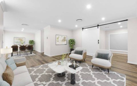 Spacious, modern living room with white walls, grey rug, and two armchairs. A sliding barn door is also visible.
