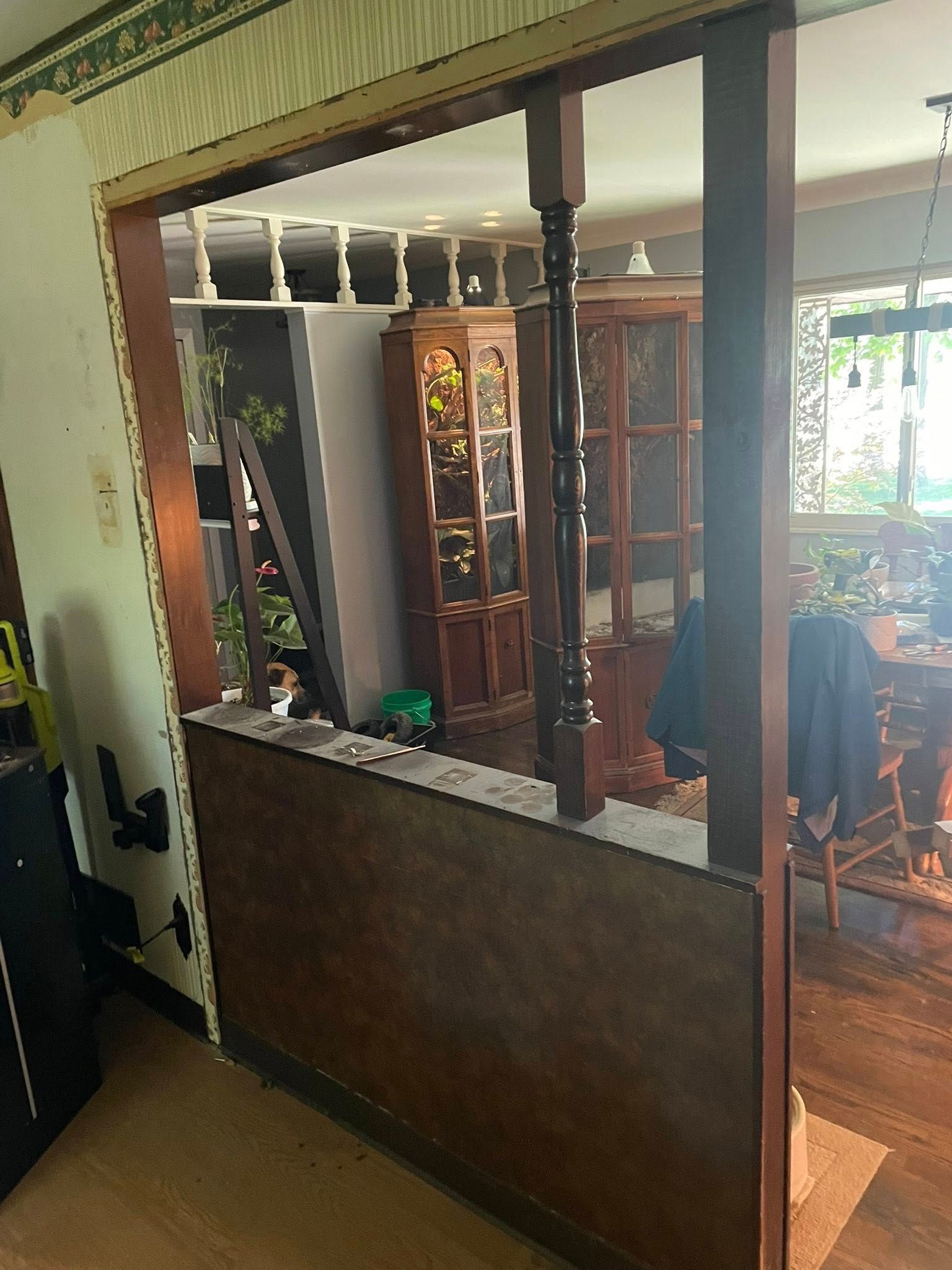 Wooden room divider with opening to dining area; dark wood furniture and interior visible beyond.
