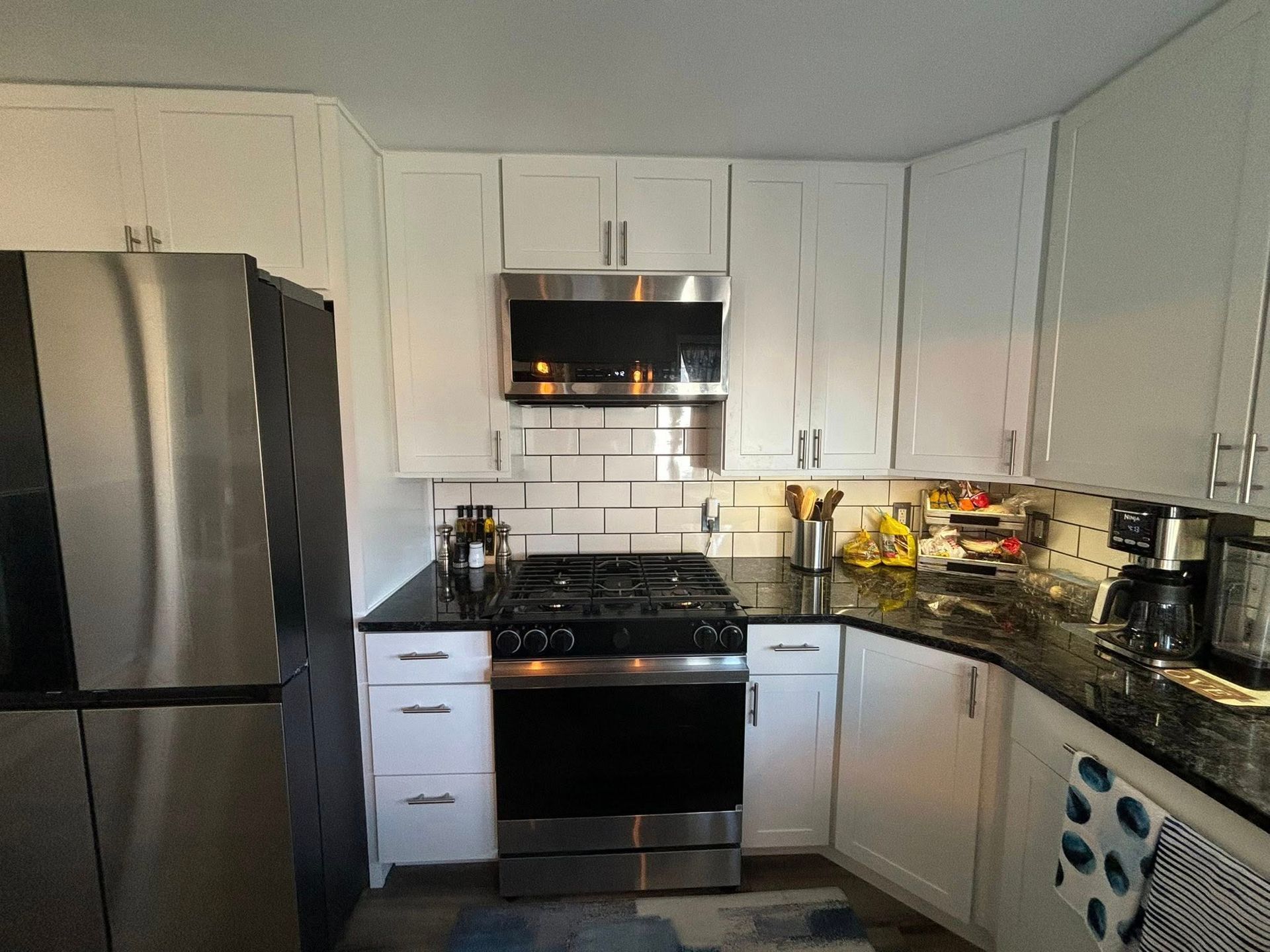 Kitchen with white cabinets, stainless steel appliances, and dark countertops.
