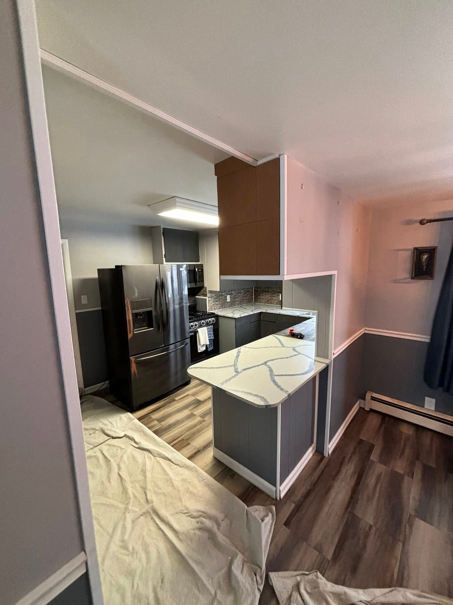 Kitchen with gray cabinets, white countertop, and black refrigerator.