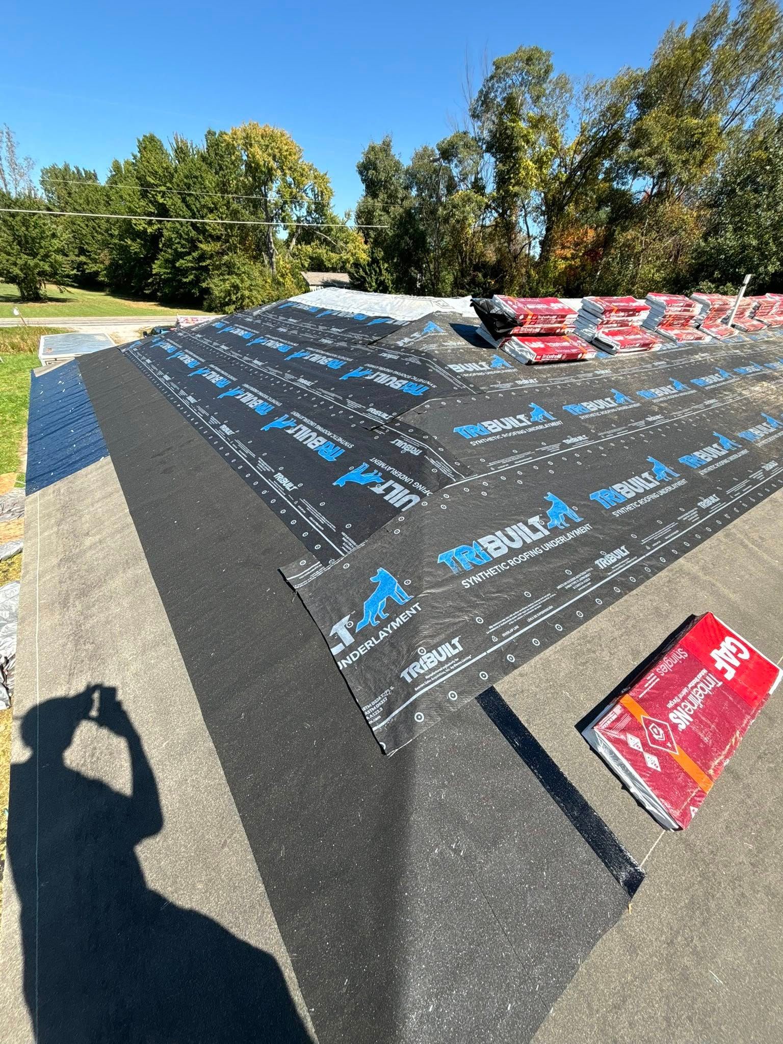 Roof under construction; black roofing membrane with blue text laid on a roof, sunny day.