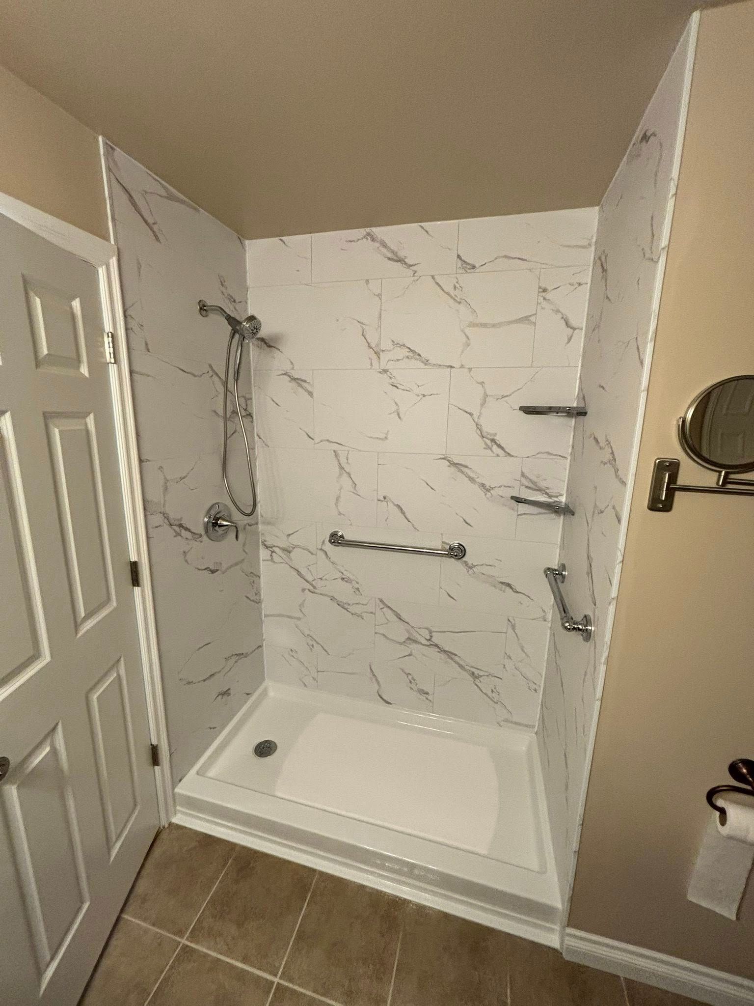 Shower with white marble-look walls, a white base, silver fixtures, and grab bars.
