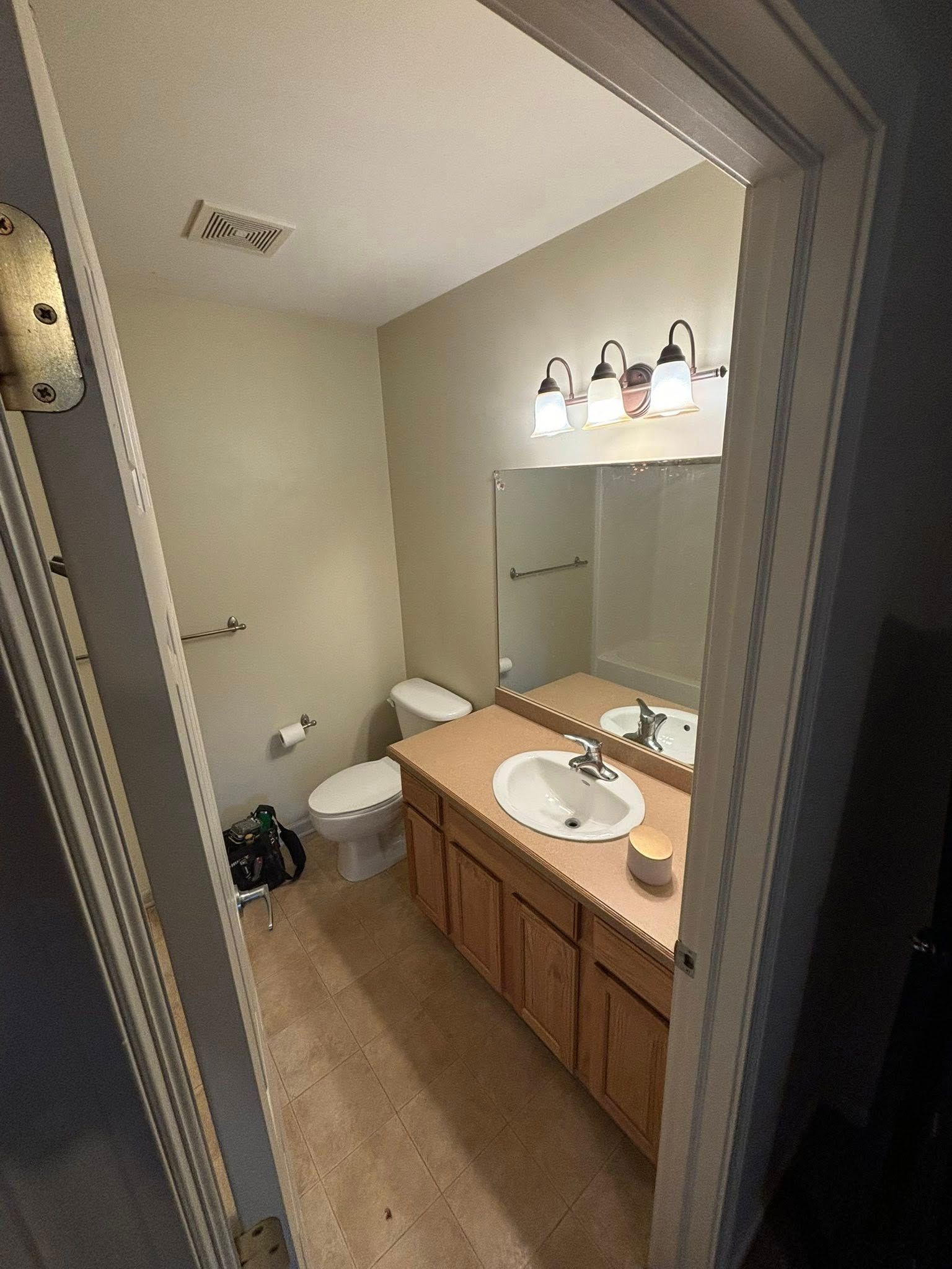 Bathroom with tan walls, brown vanity, toilet, and a mirror.