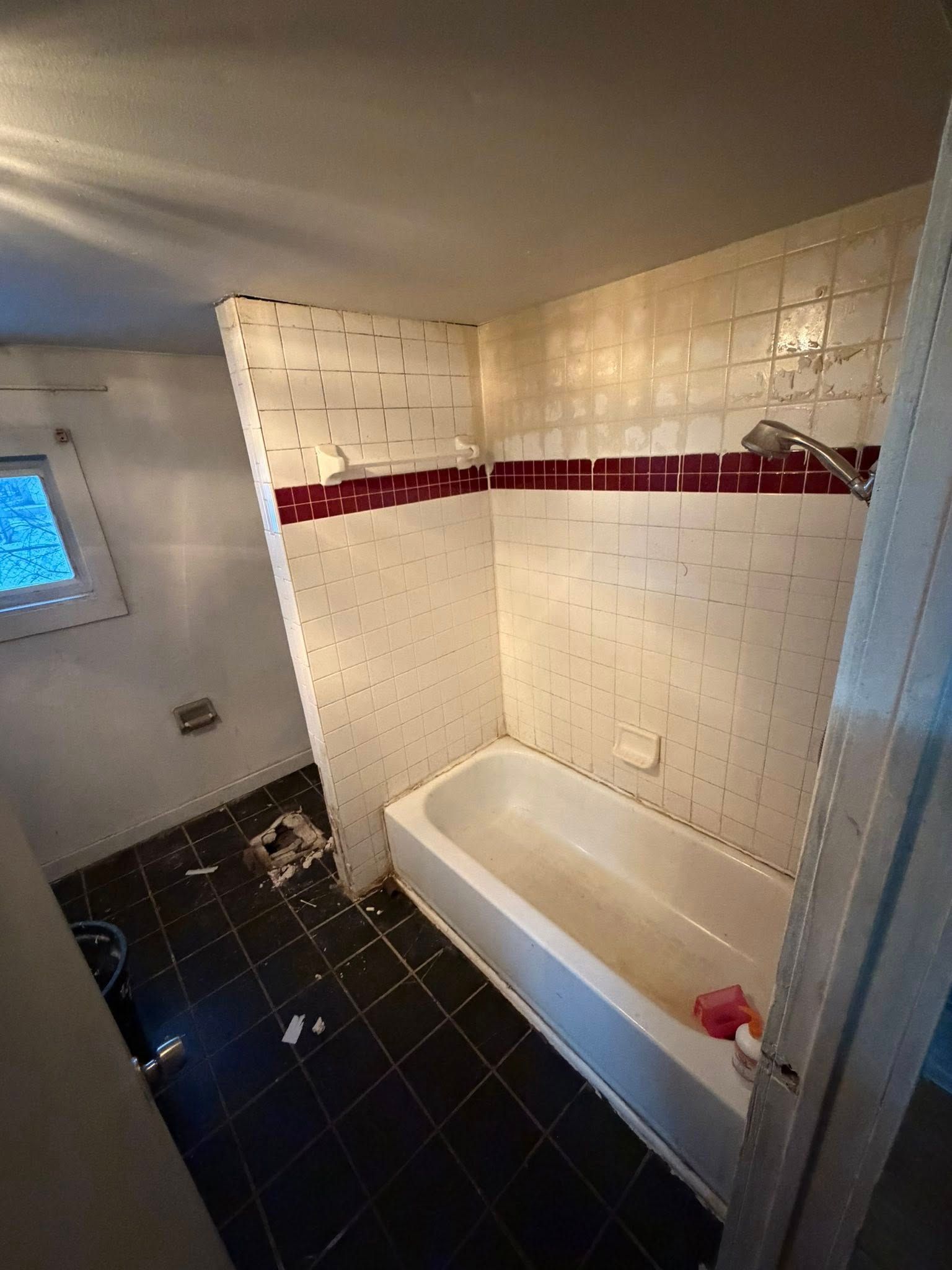 Bathroom with white tiled walls, a bathtub, and dark tile floor.