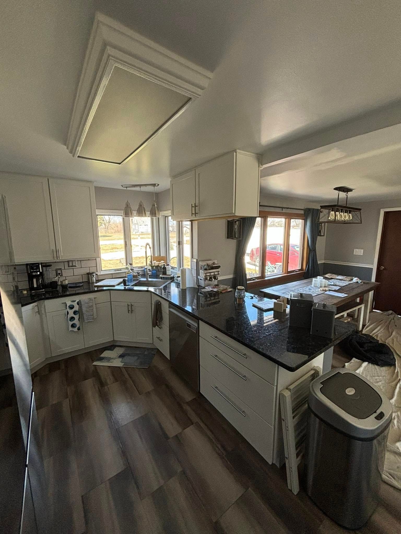 Modern kitchen with white cabinets, dark countertops, and a large island.