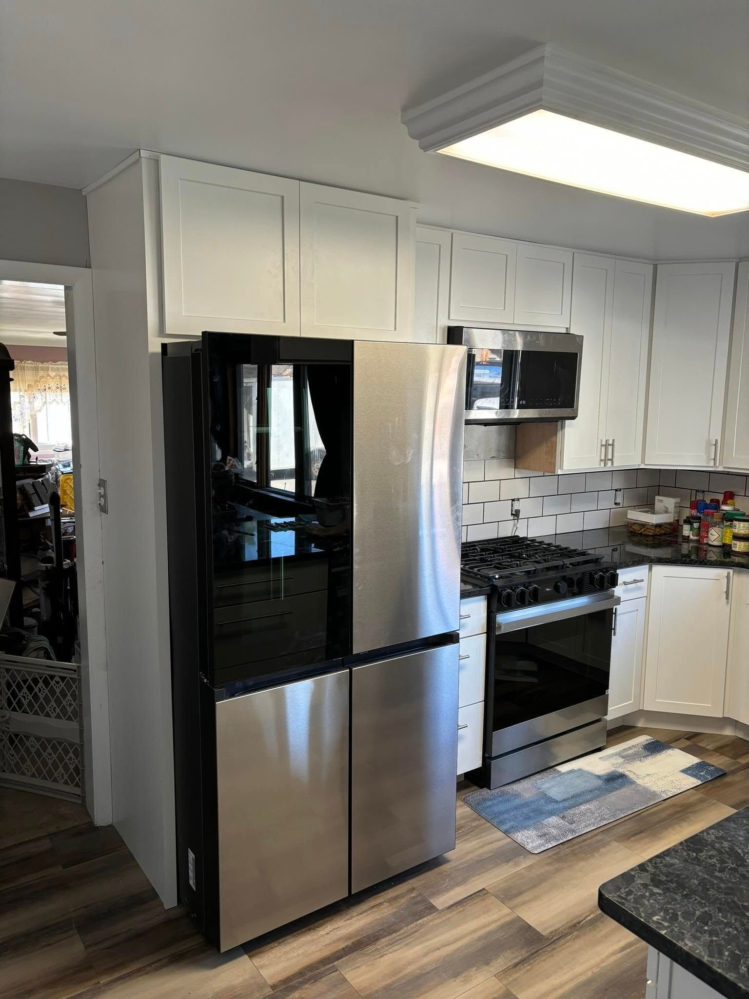 Kitchen with a stainless steel refrigerator, white cabinets, and a gas stove.
