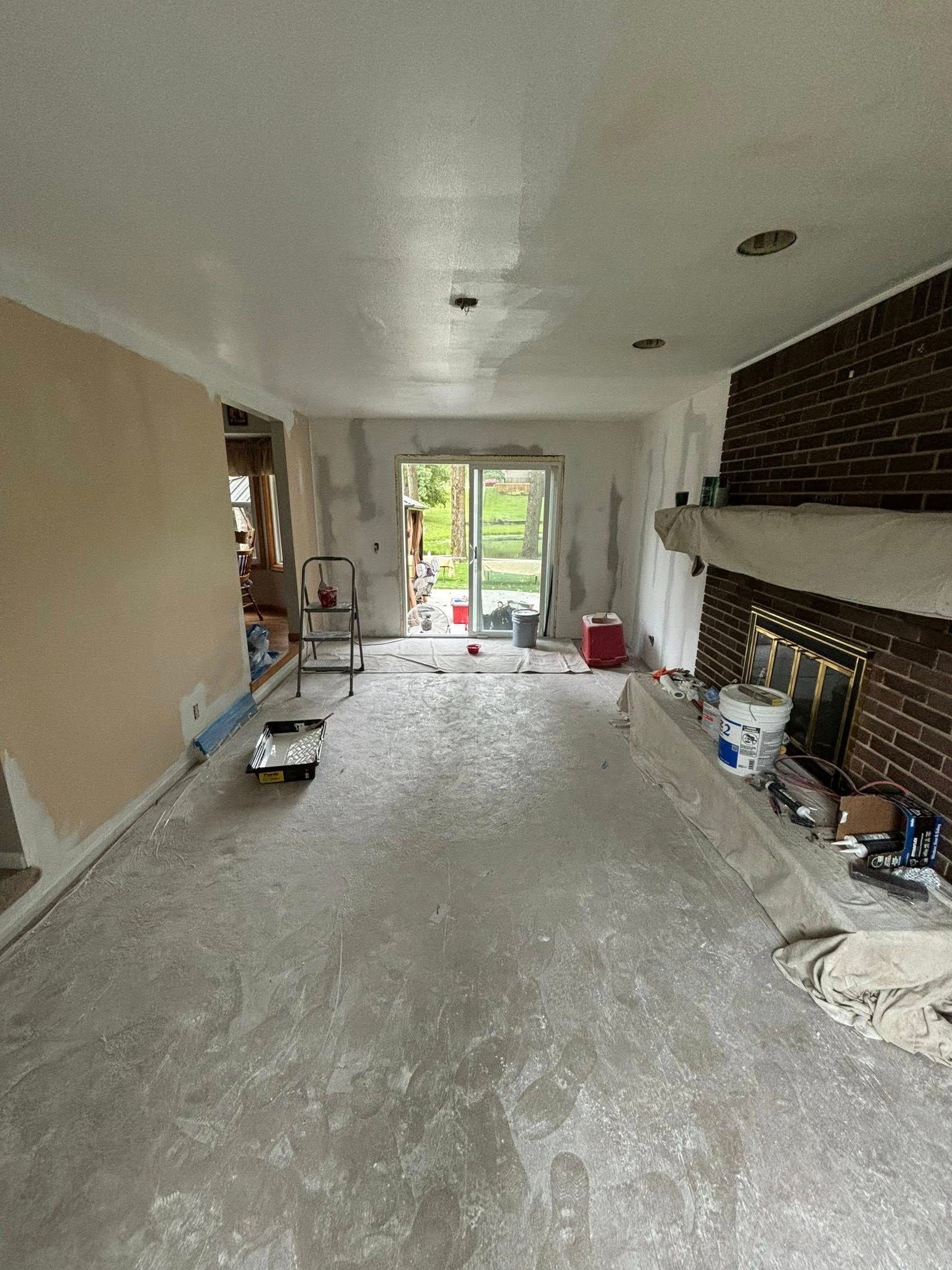 Interior room under renovation, concrete floor, white walls, brick fireplace.
