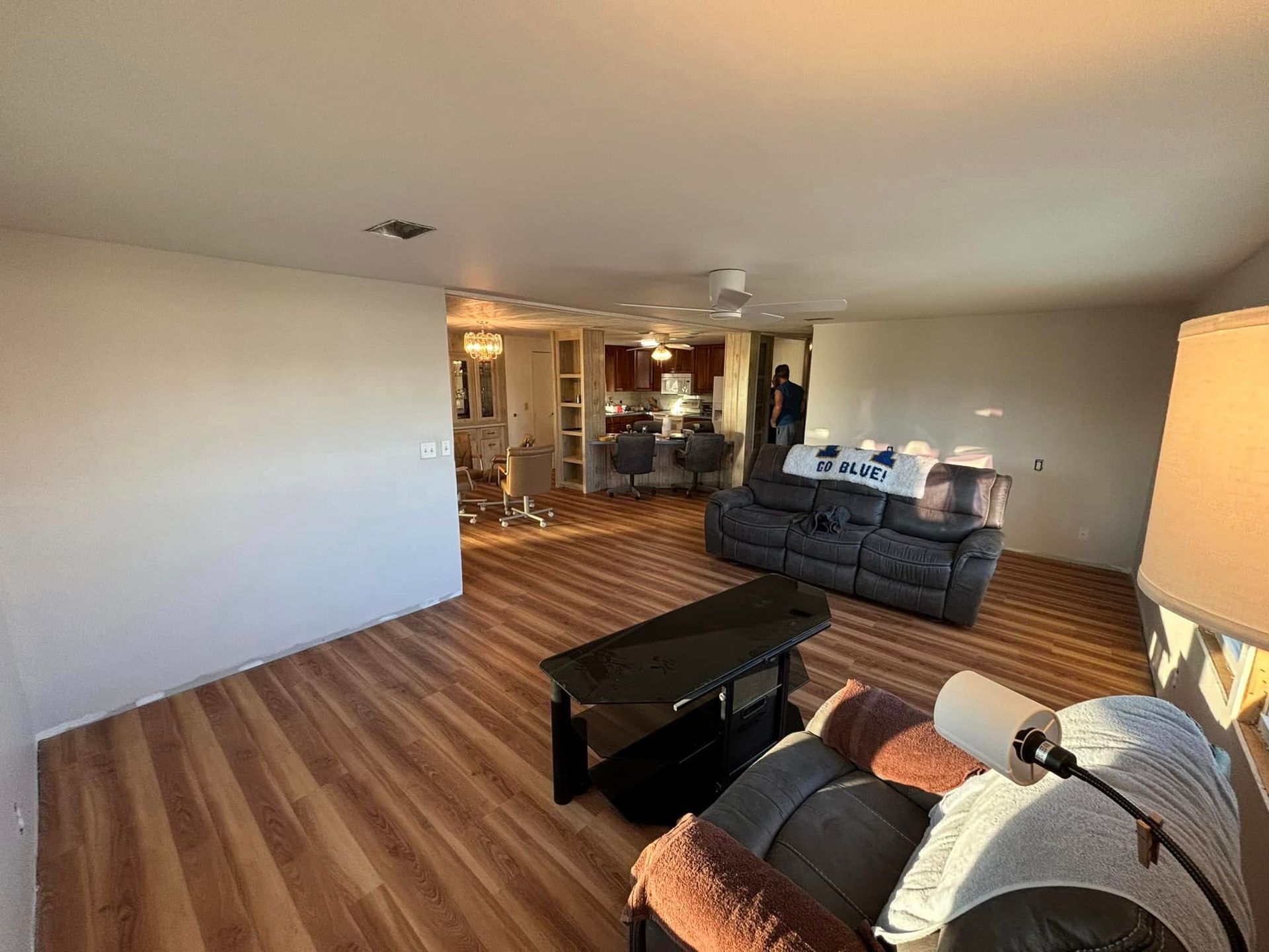 Living room with wood floors, black furniture, and a view into a kitchen.