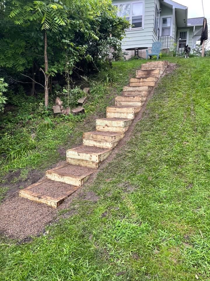 Wooden steps built into a grassy hill leading up to a house.