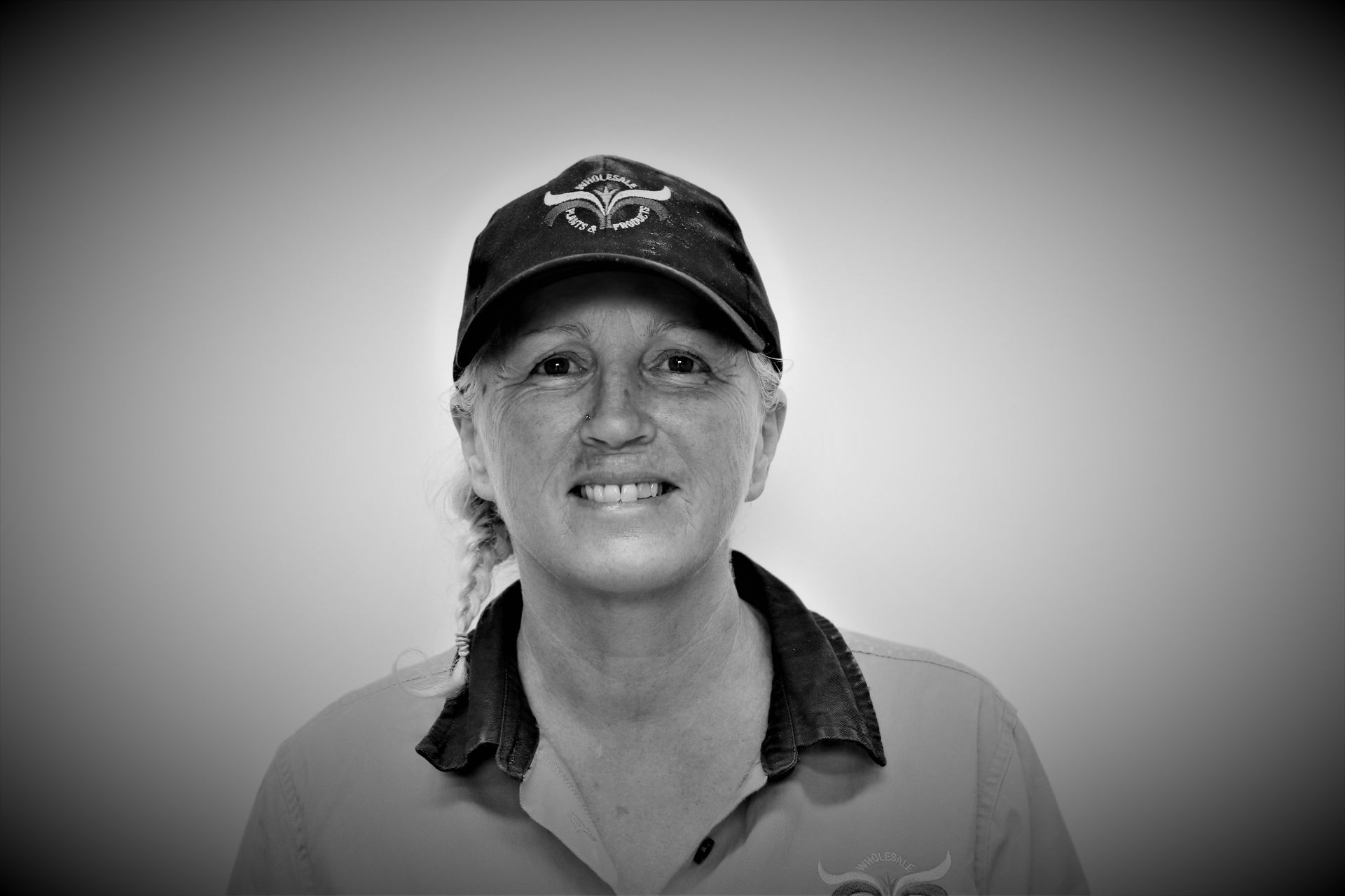 A woman wearing a hat and a shirt is smiling in a black and white photo.