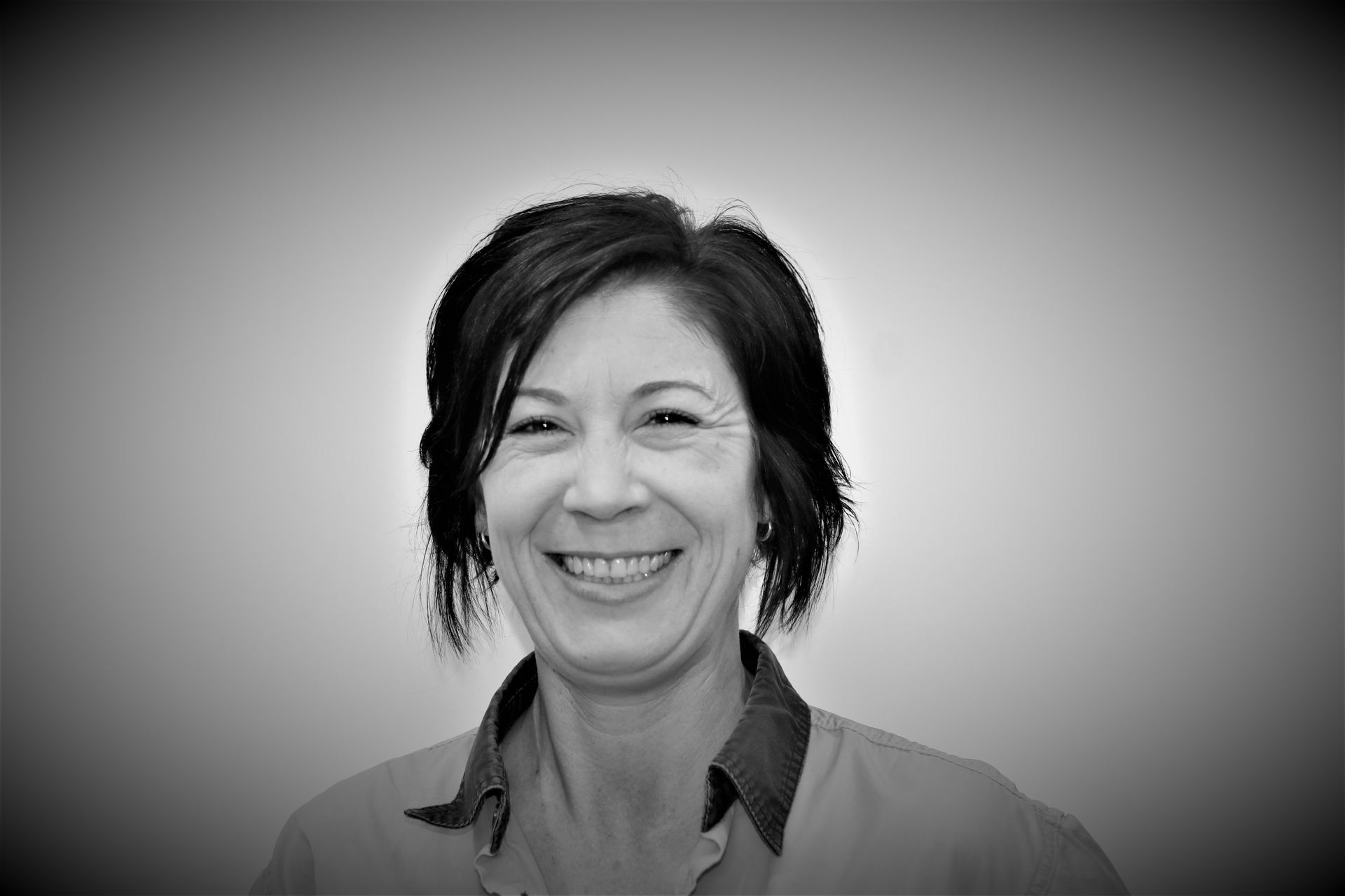 A woman is smiling in a black and white photo.