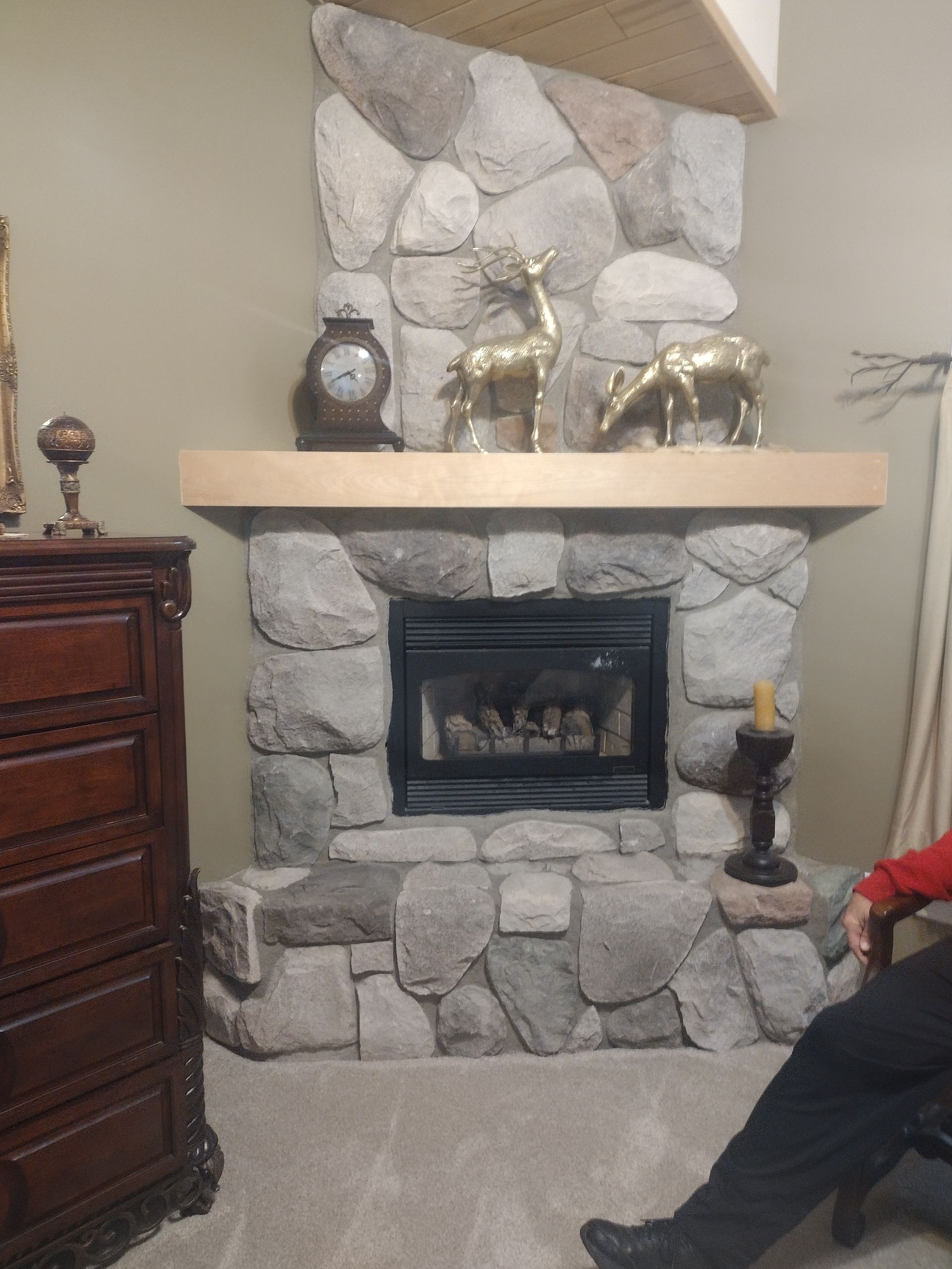A man is sitting in front of a stone fireplace in a living room.
