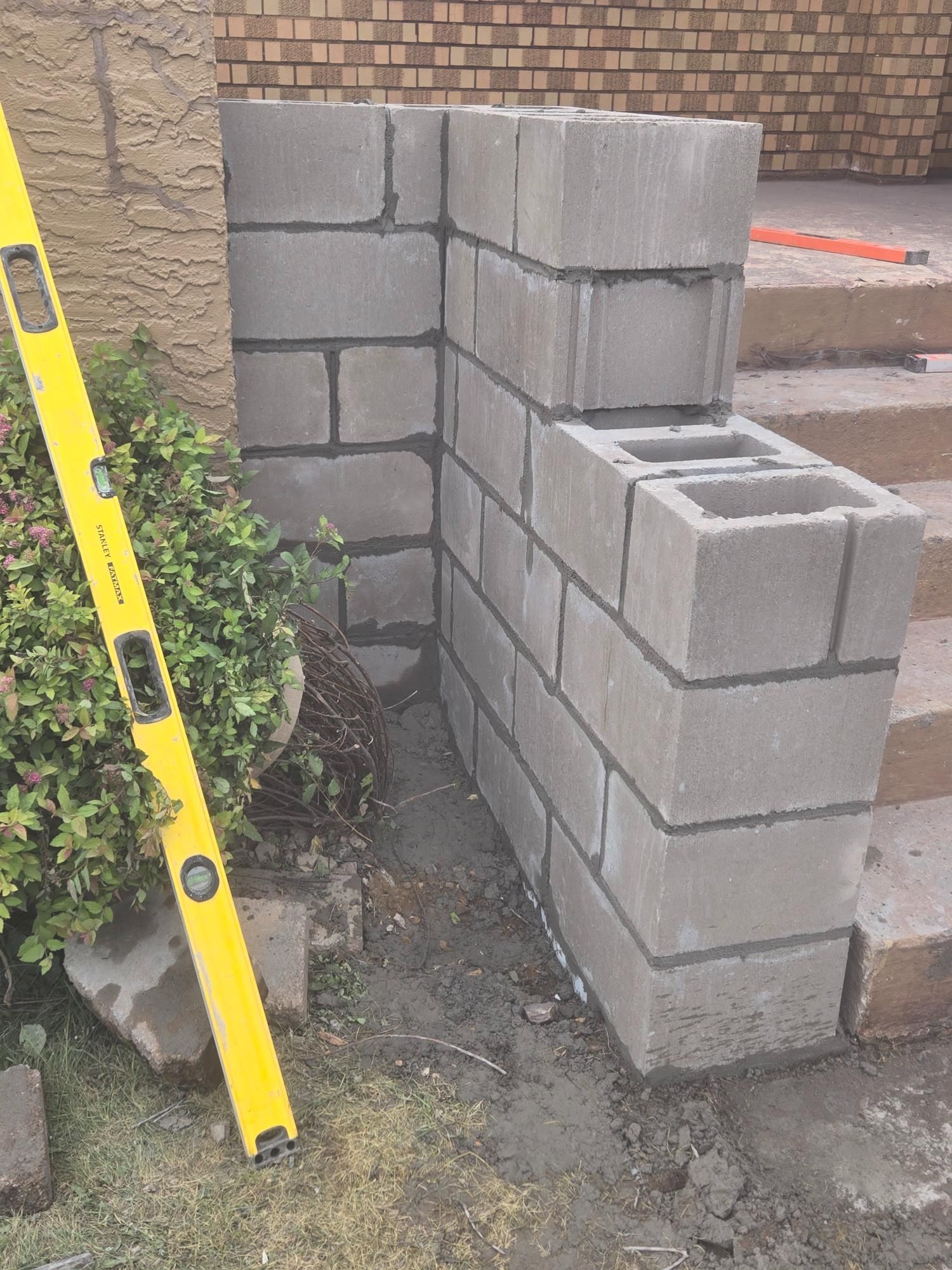 A yellow level is sitting next to a brick wall.