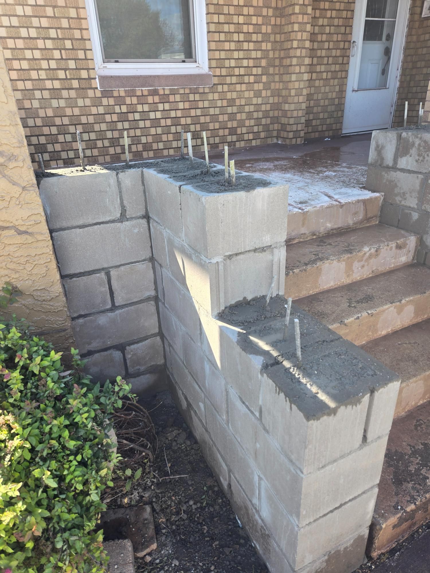 A brick wall is being built next to a set of stairs.