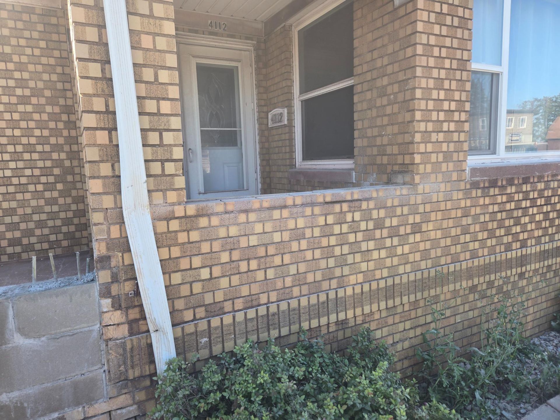 A brick house with a porch and a window.