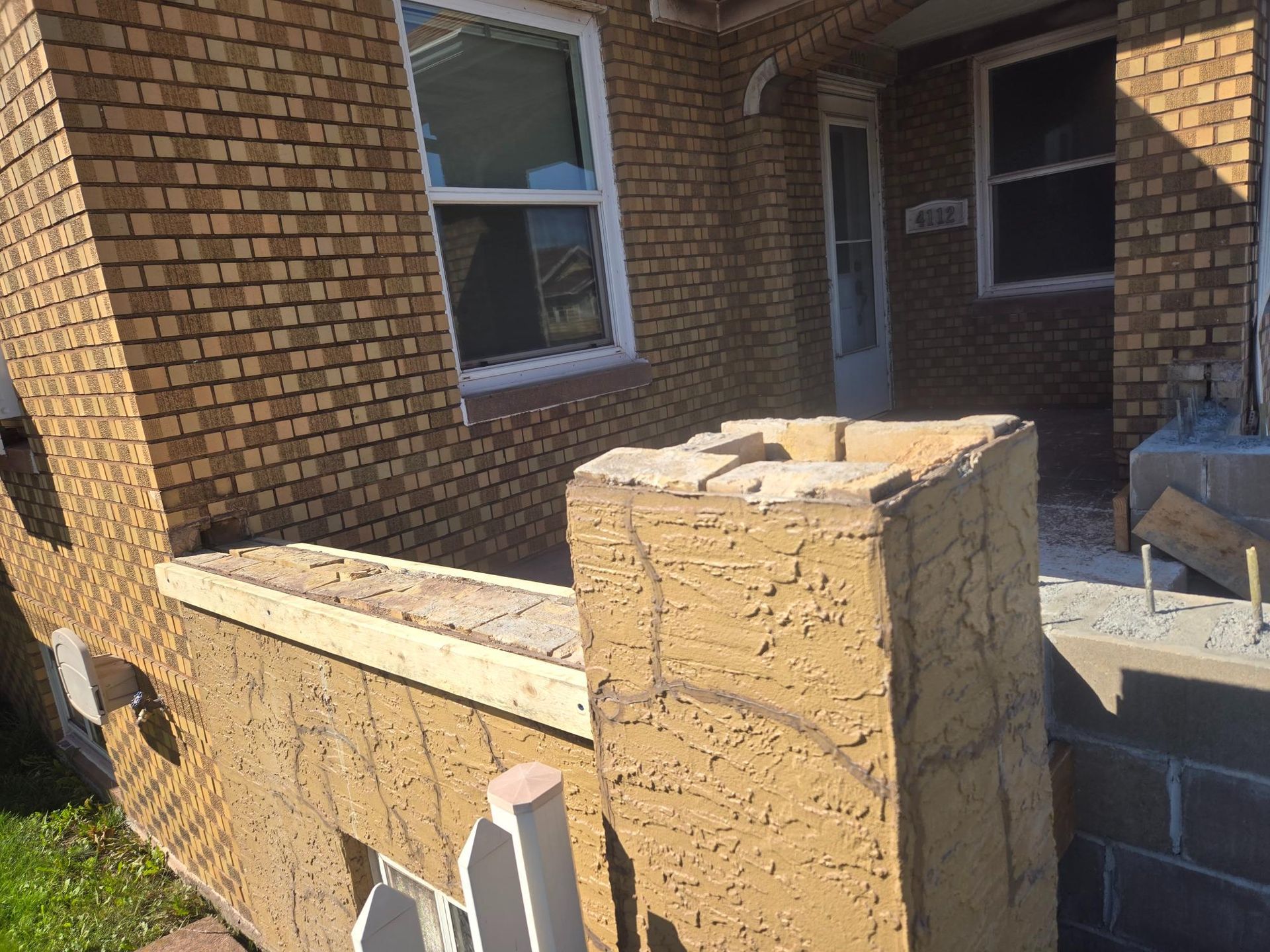A brick building with a concrete pillar in front of it.