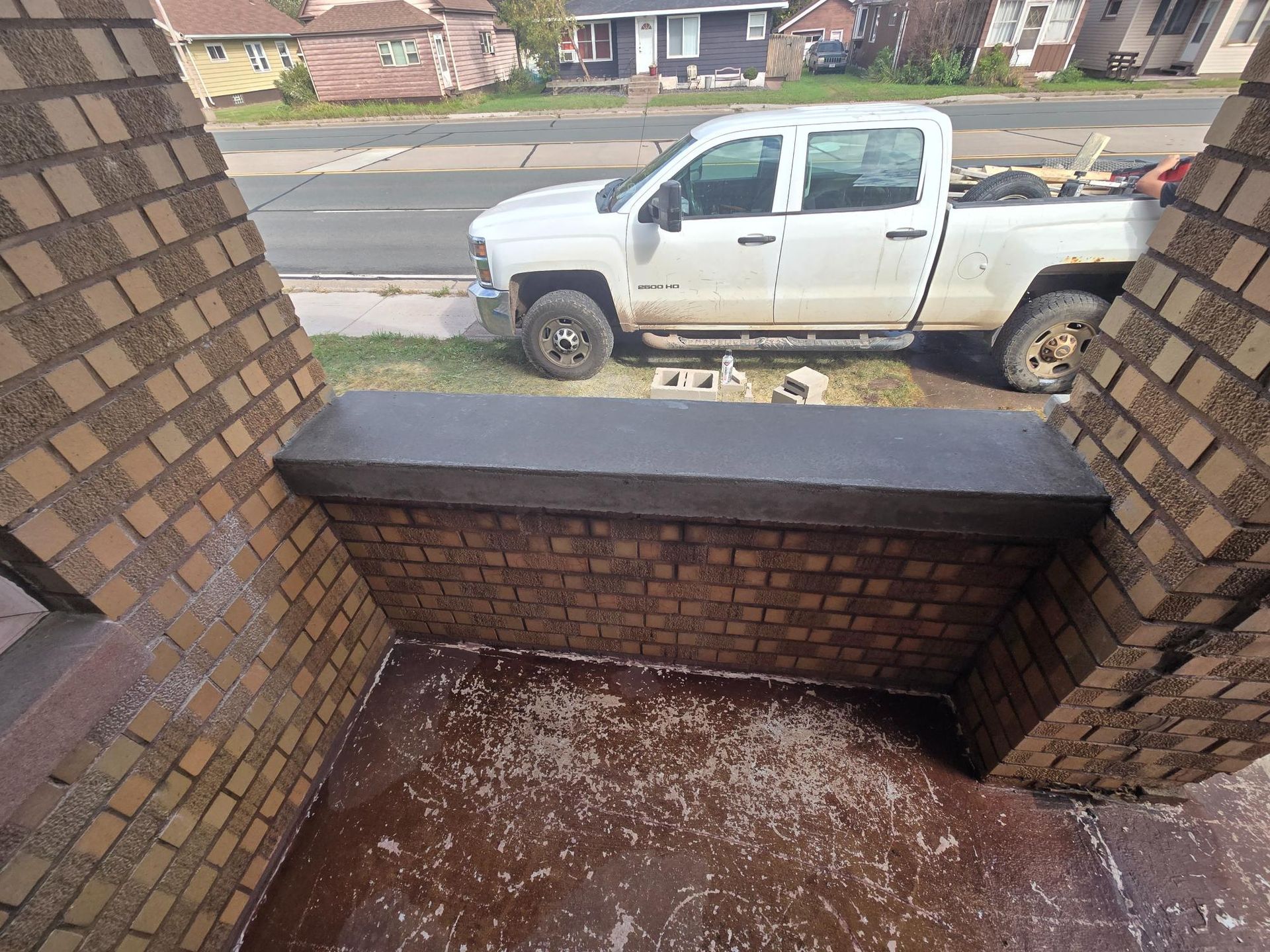 A white truck is parked on the side of a brick building.