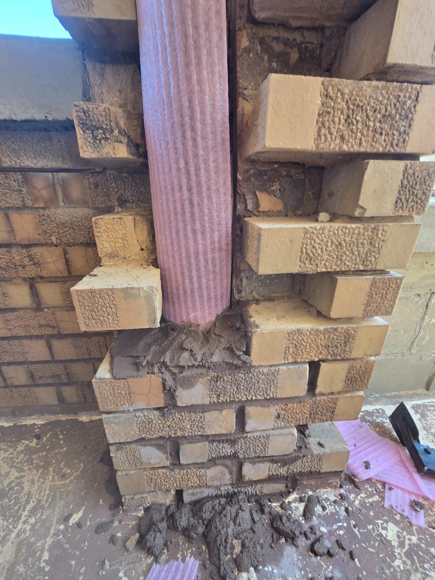 A brick wall with a pipe coming out of it.