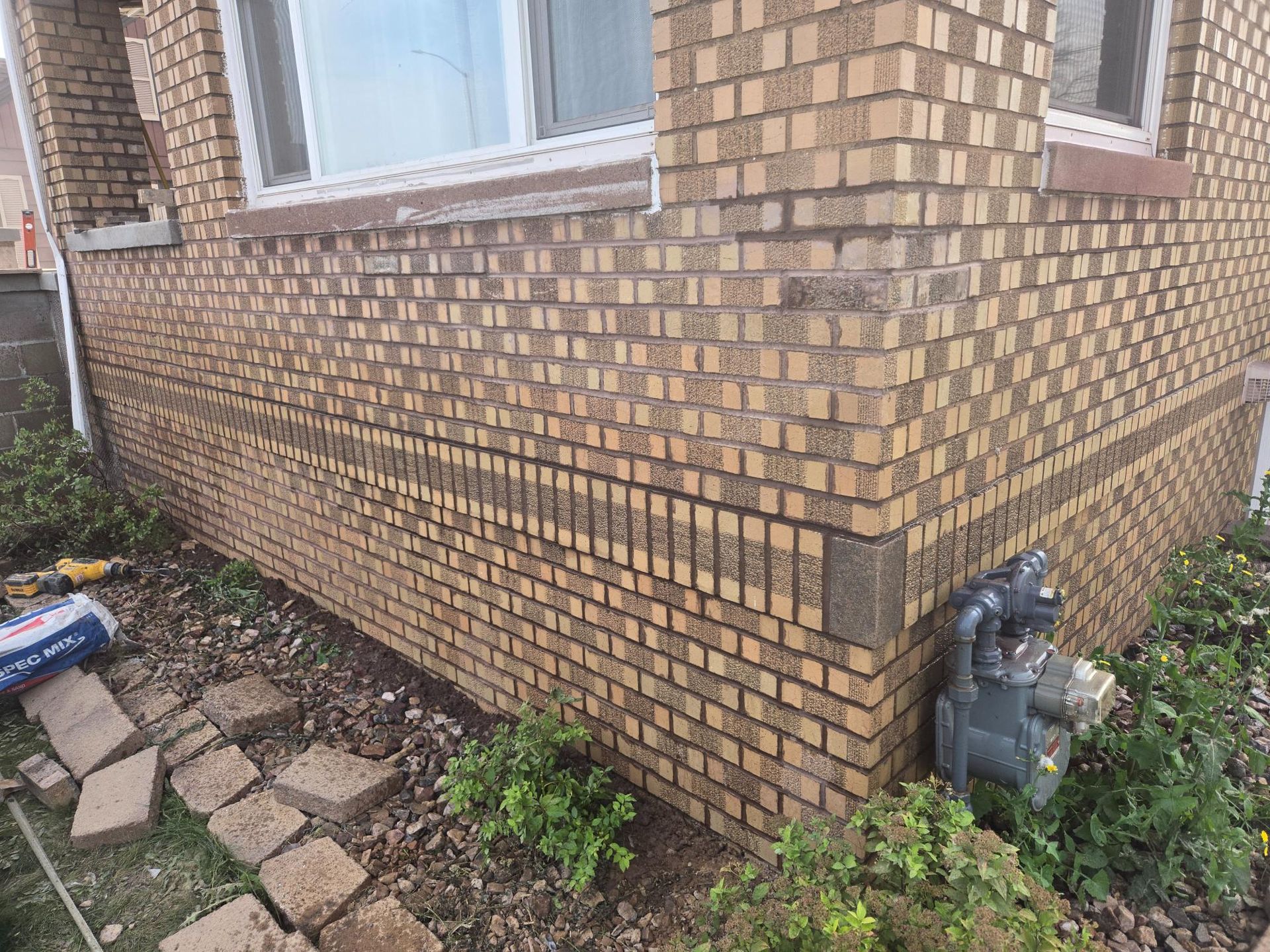 A brick building with a window and a gas meter on the side of it.