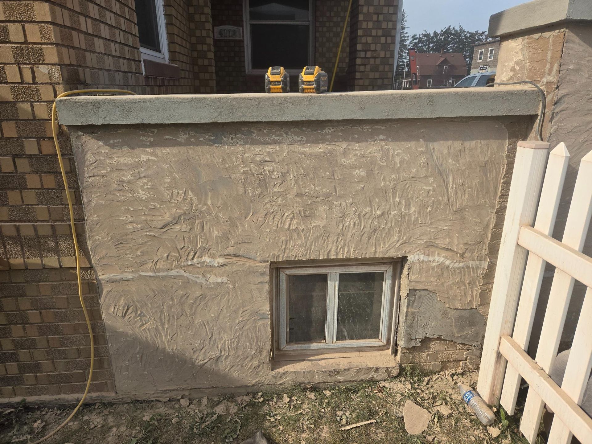 A brick wall with a window and a fence in front of it.