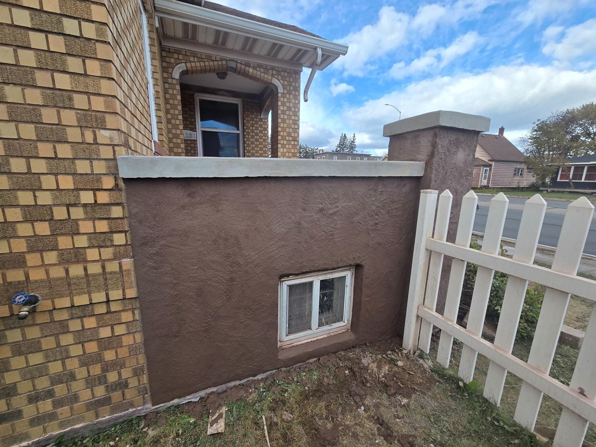 A brick building with a white picket fence and a window in the wall.
