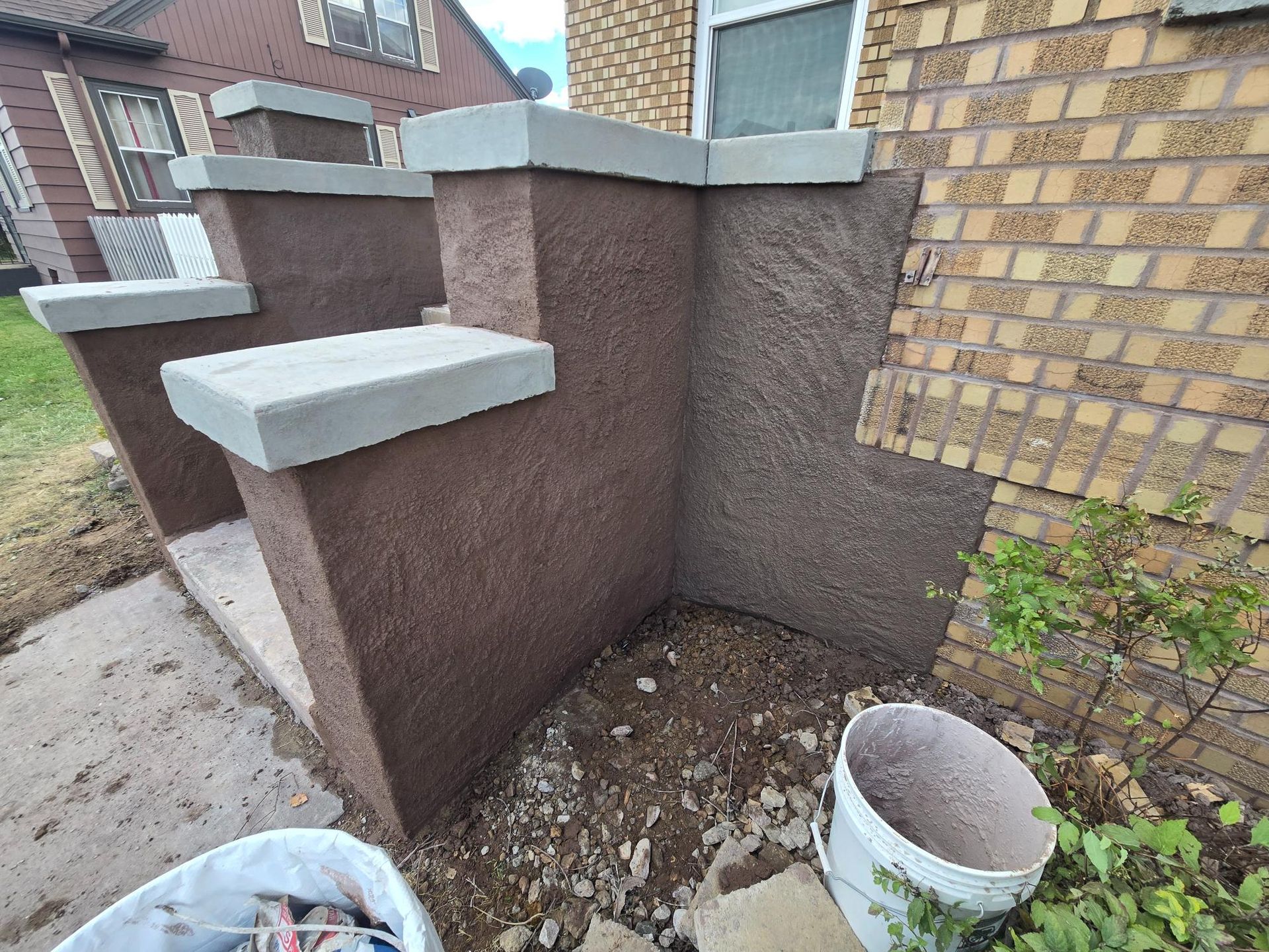 A brick building with stairs and a bucket in front of it.