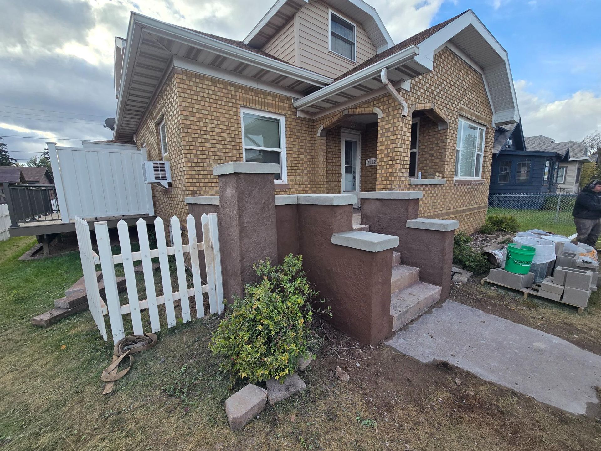A brick house with a white picket fence in front of it.