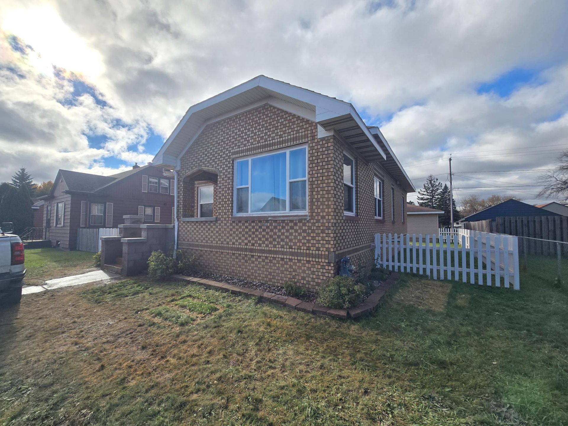 A small brick house with a white picket fence in front of it.