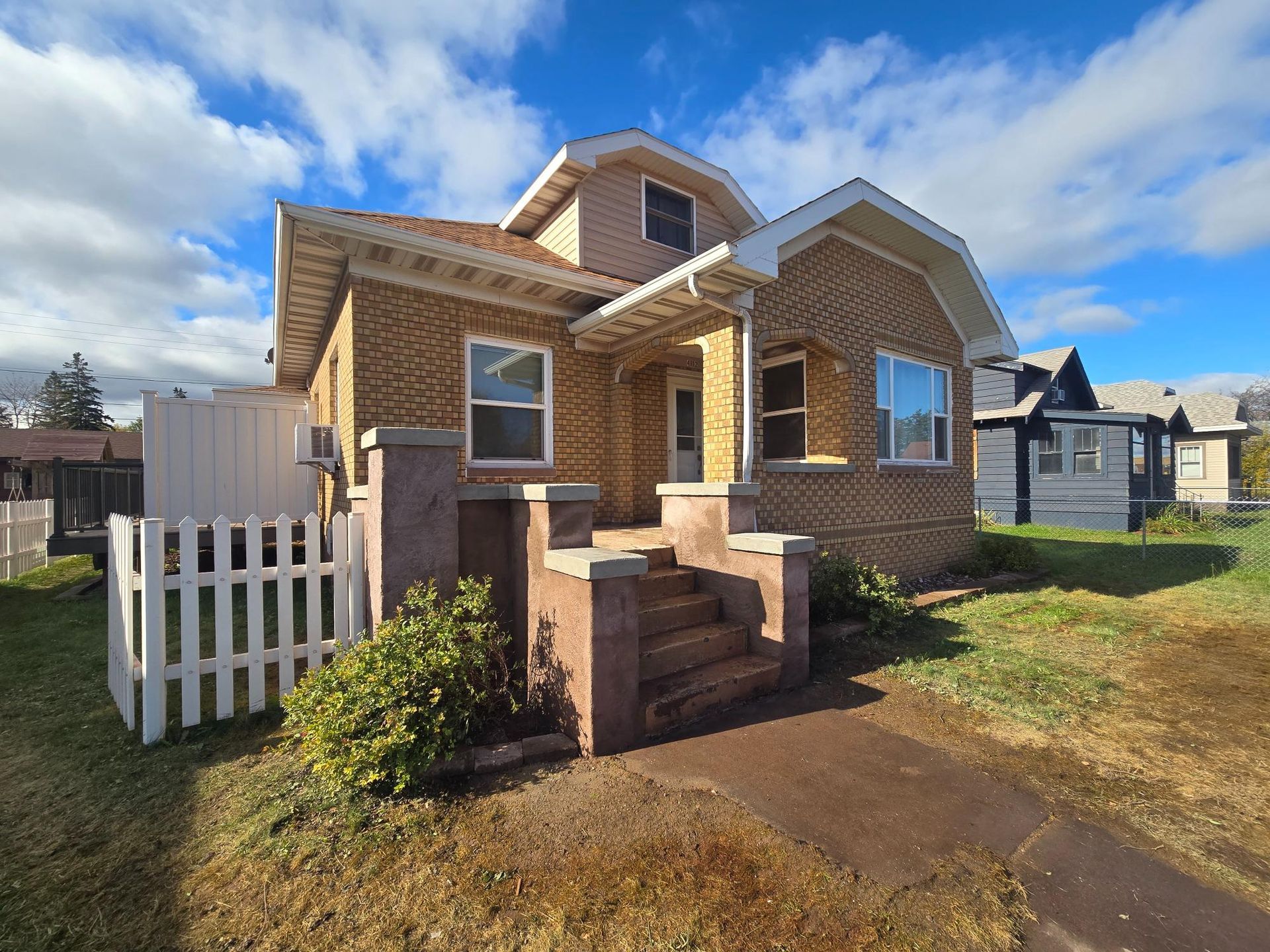 A brick house with a white picket fence in front of it.