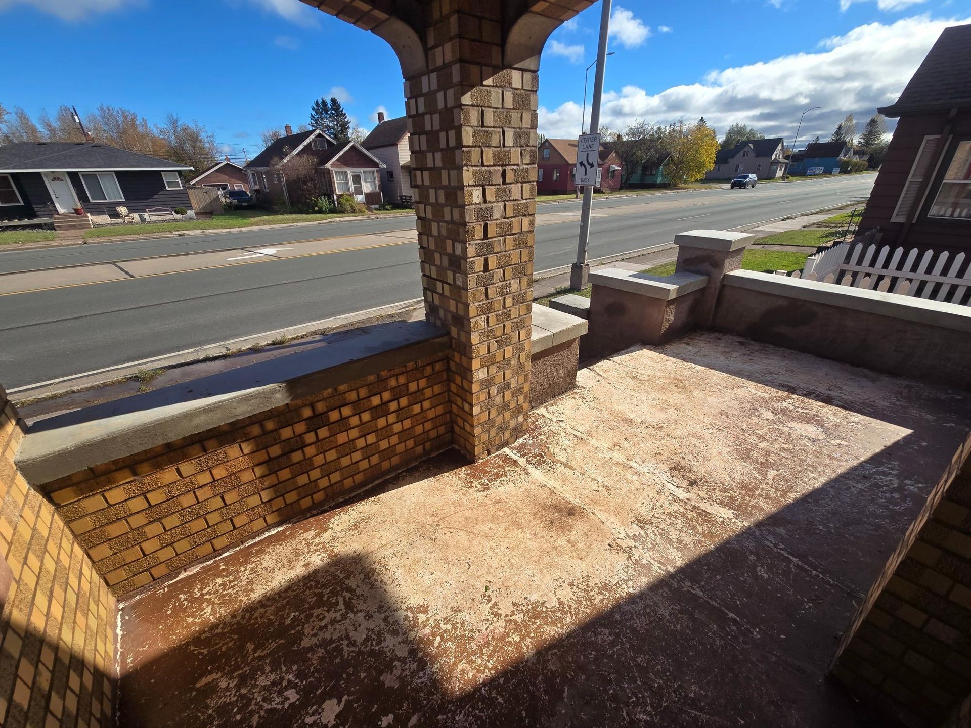 A brick porch with a shadow on the floor
