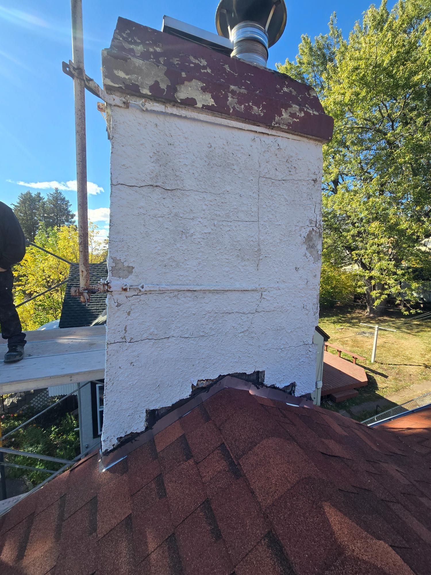 A man is working on a chimney on top of a roof.