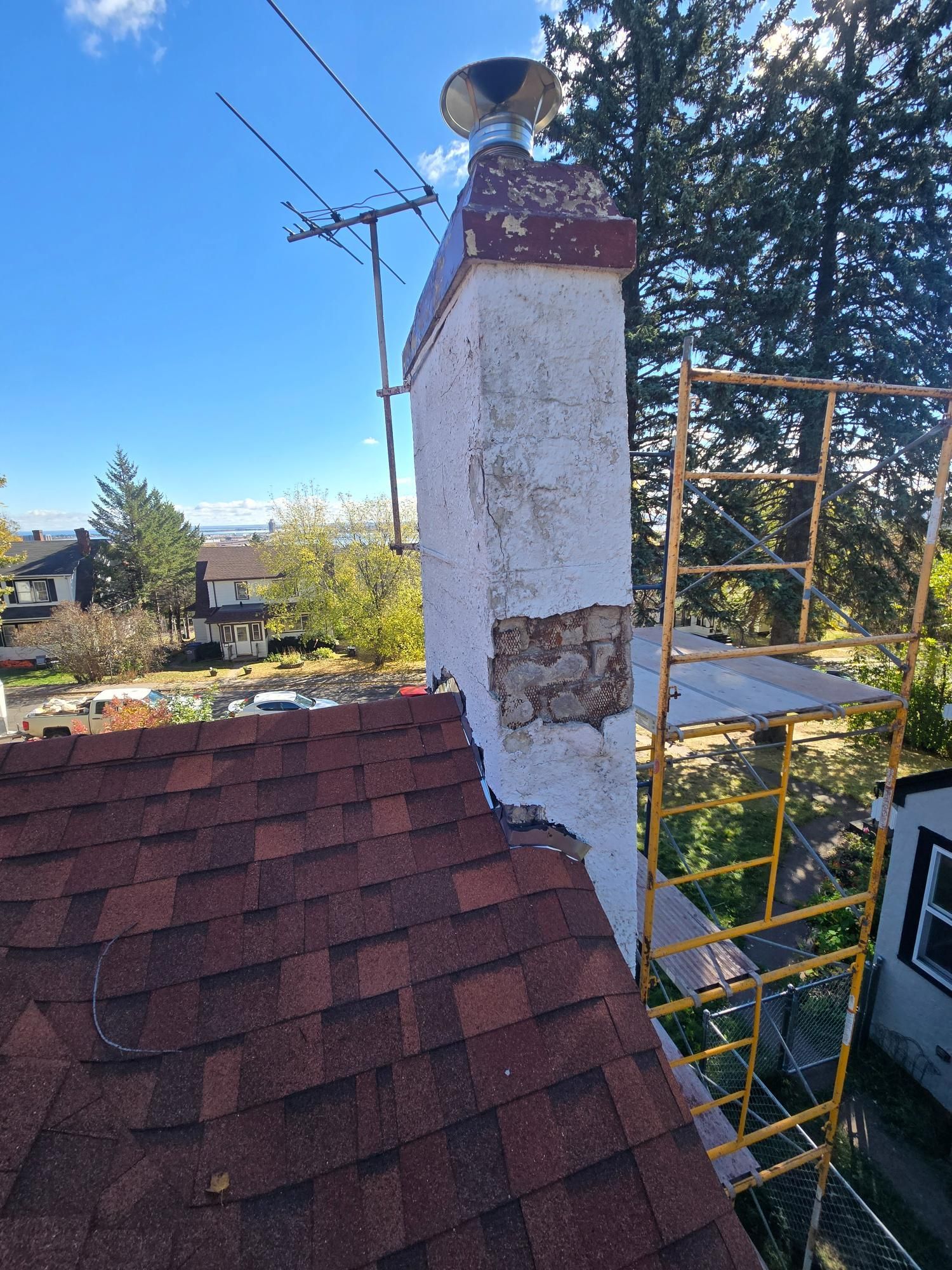 A chimney is being repaired on the roof of a house.