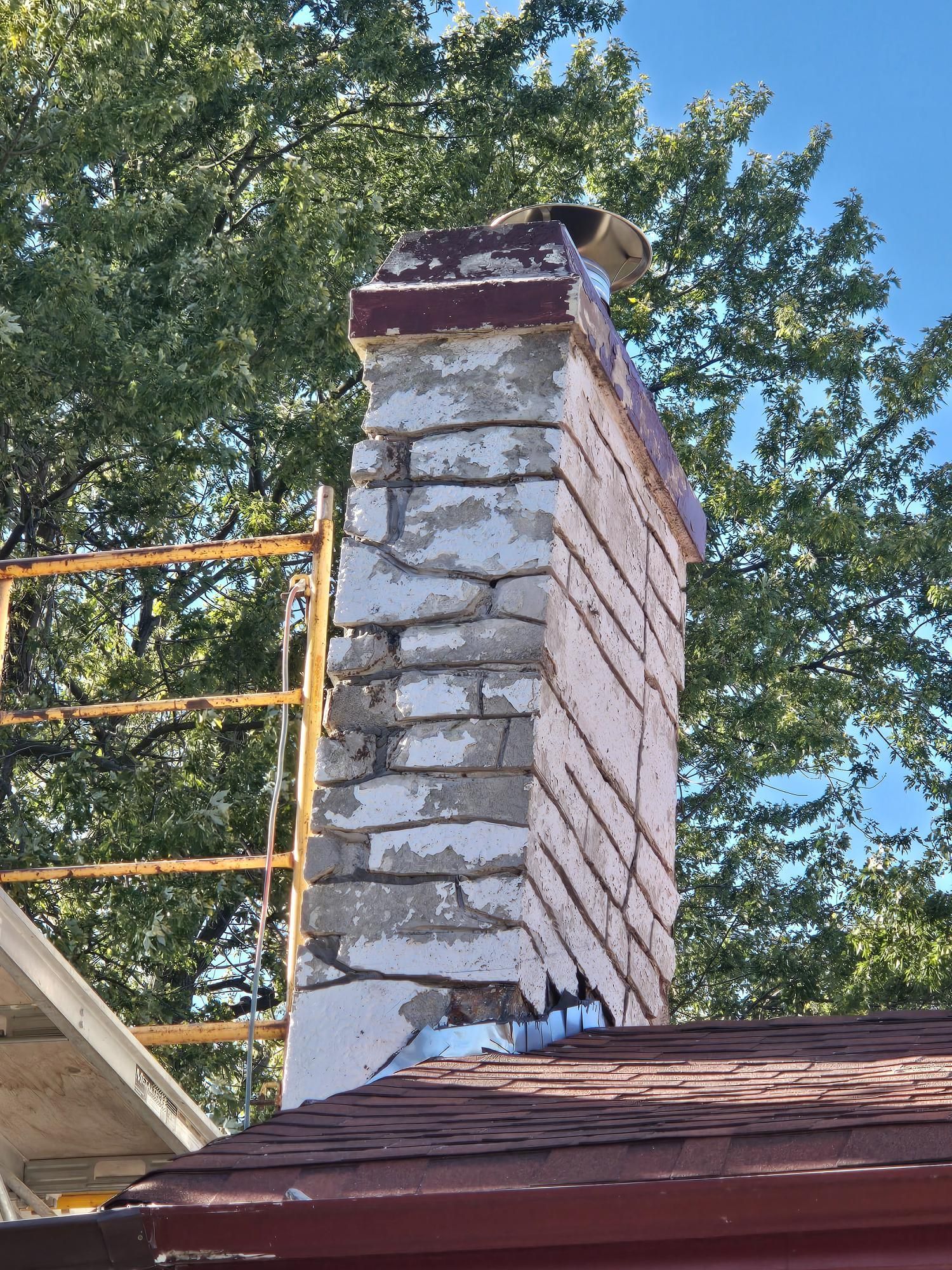 A brick chimney is being repaired on the roof of a house.
