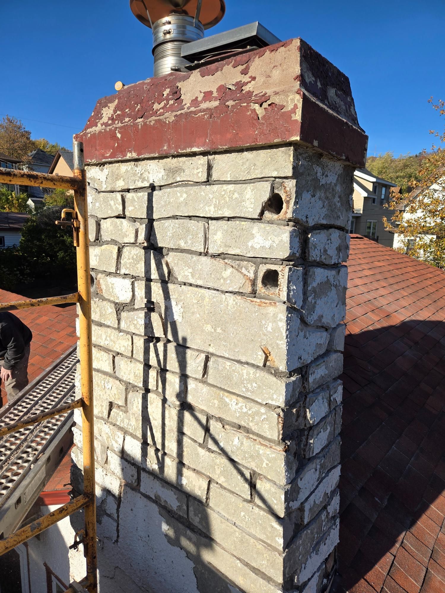 A brick chimney is sitting on top of a roof.