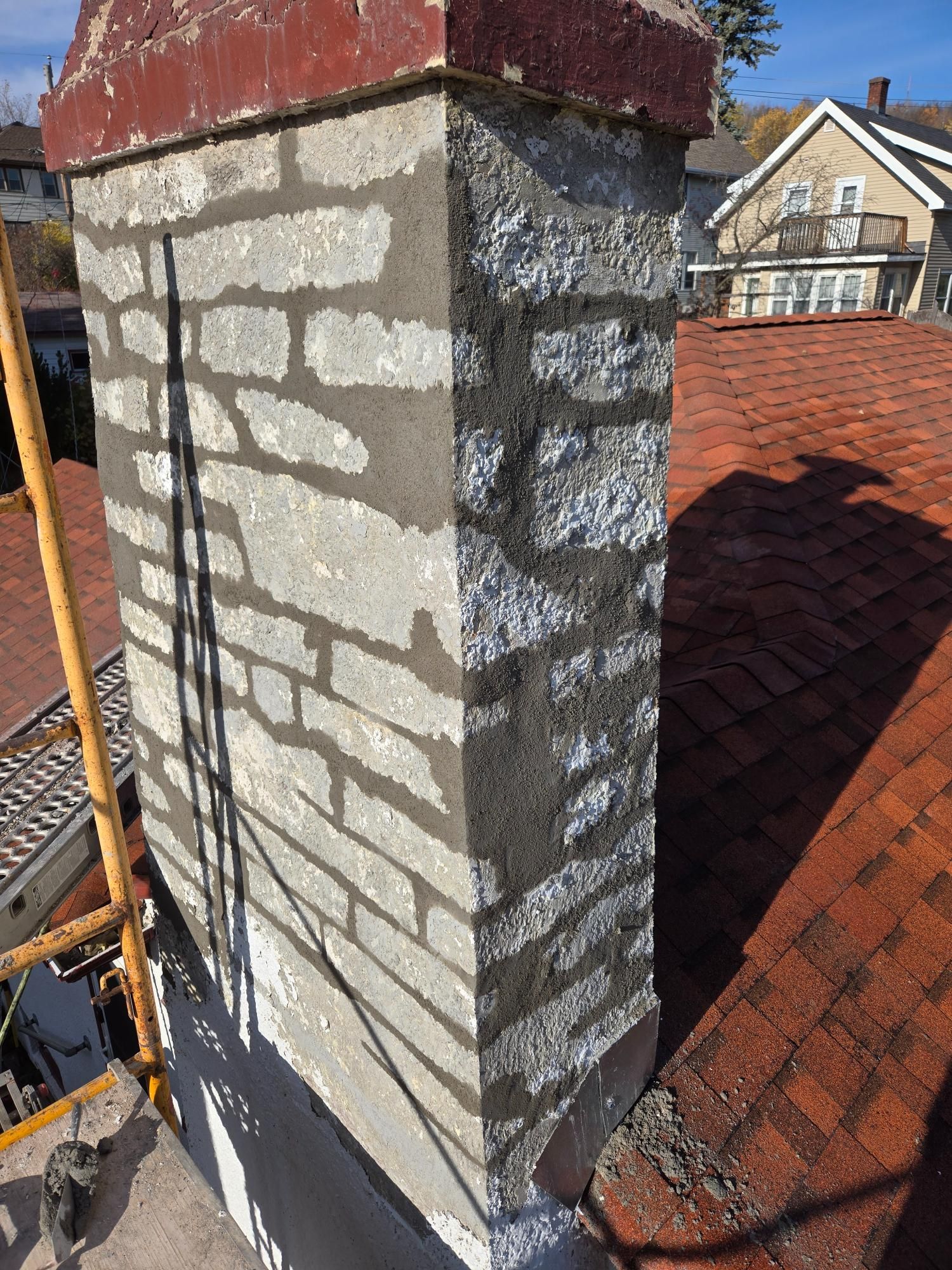 A brick chimney is sitting on top of a brick roof.