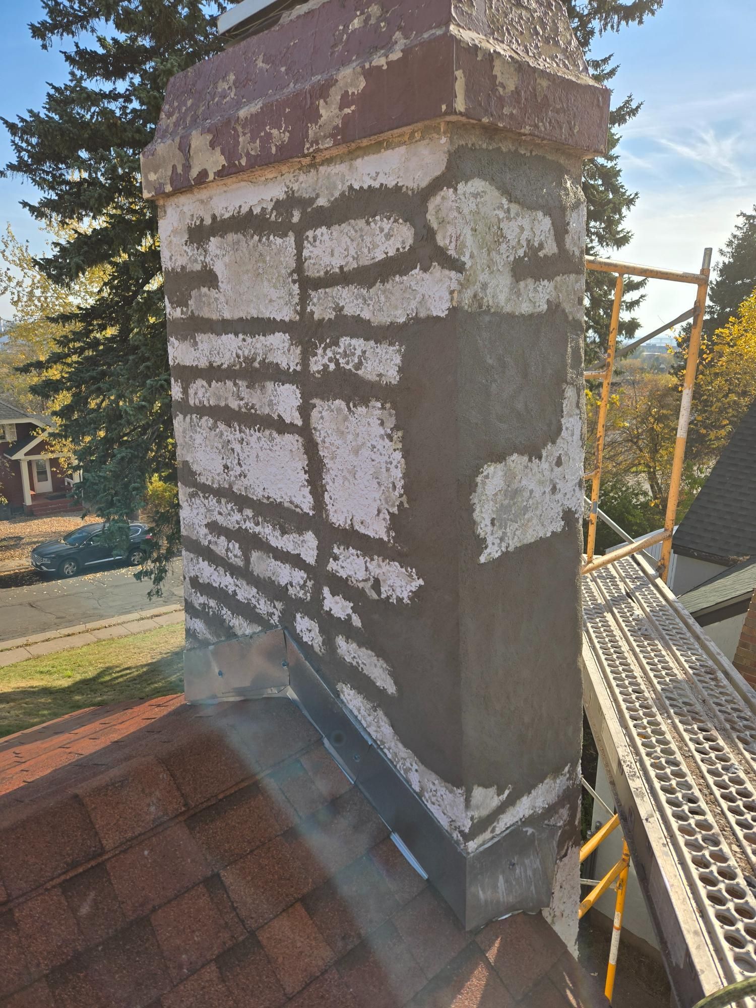 A chimney is being repaired on the roof of a house.