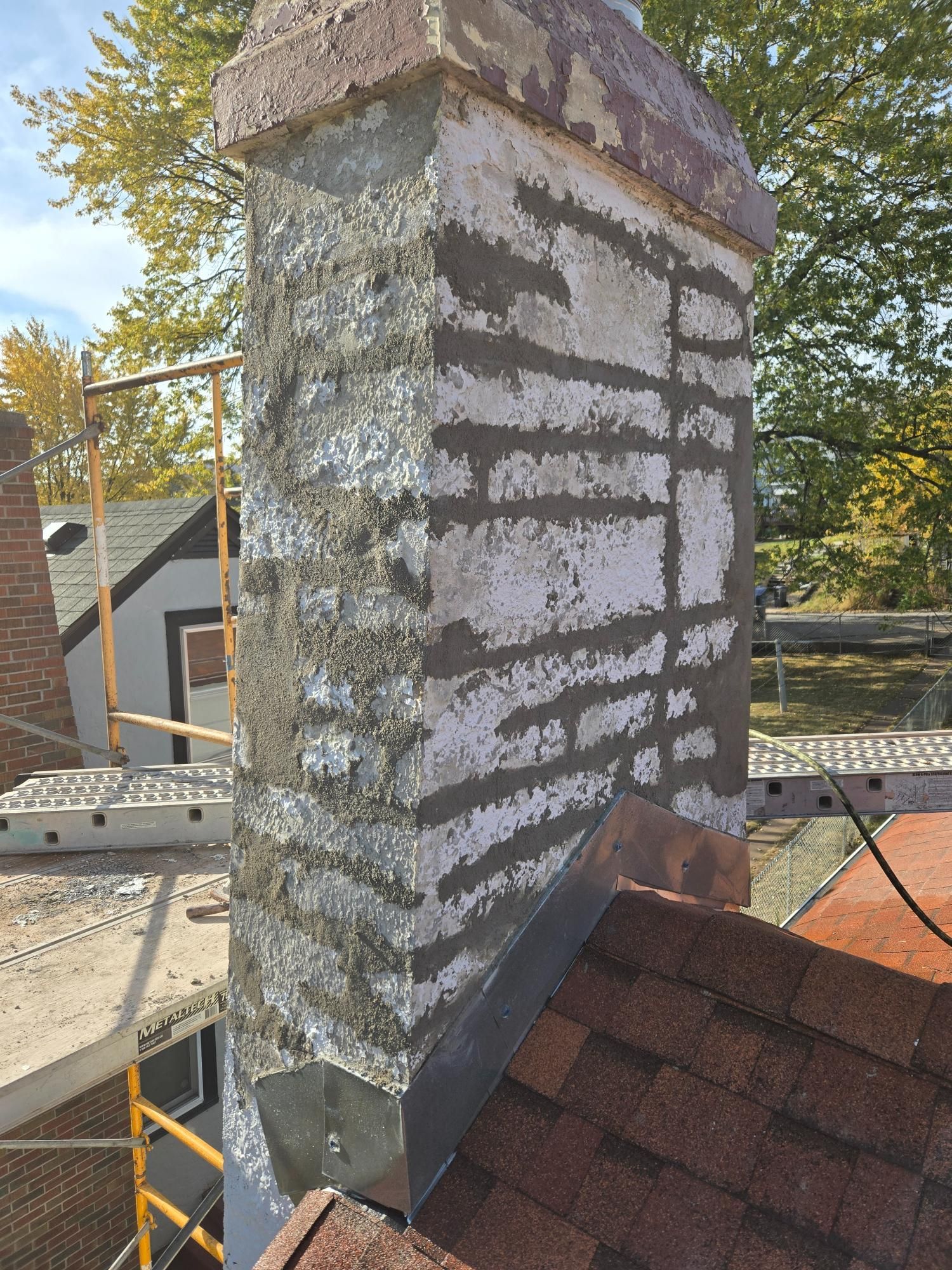 A chimney is being repaired on the roof of a house.