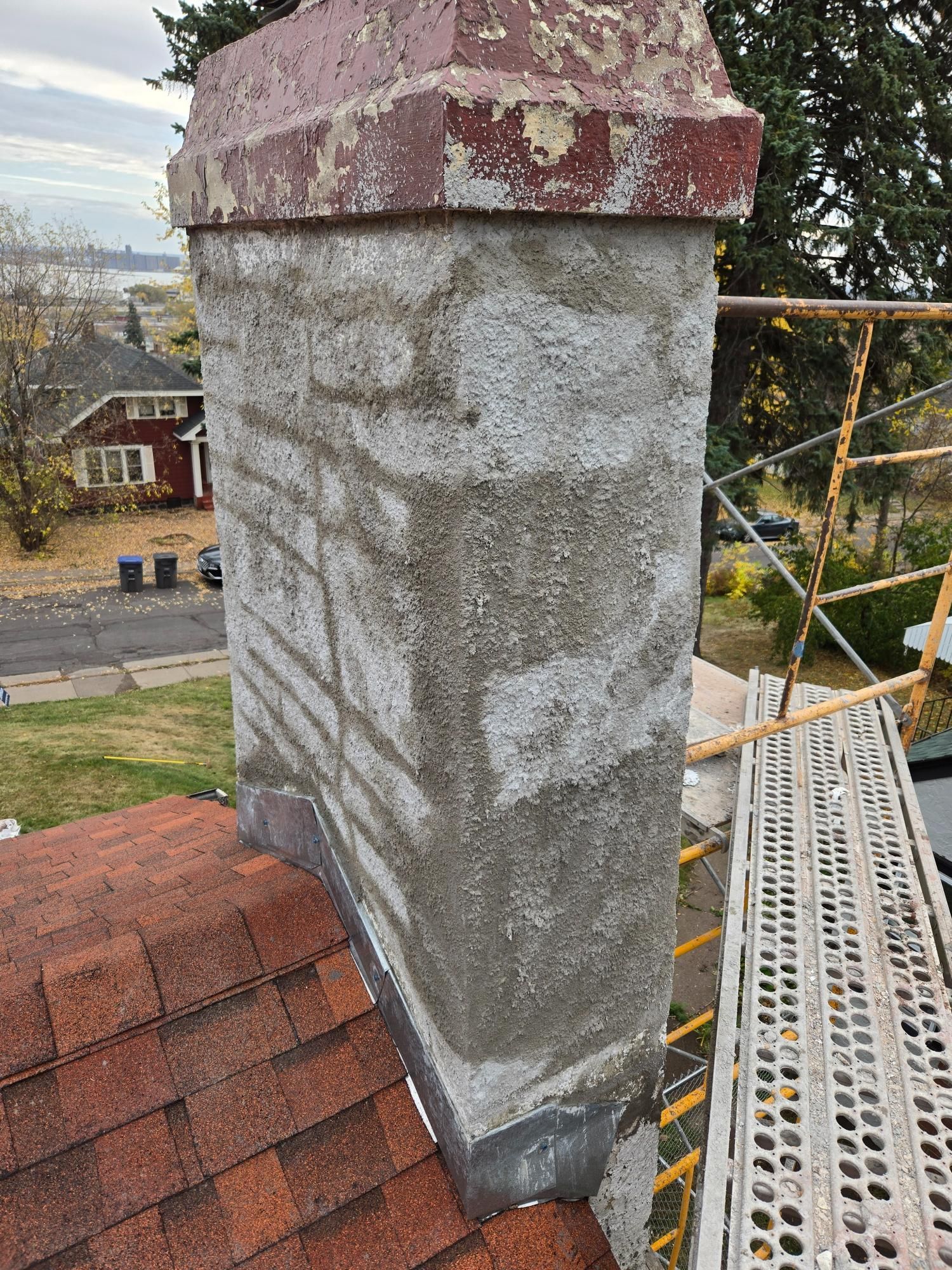 A chimney is sitting on top of a roof next to a scaffolding.