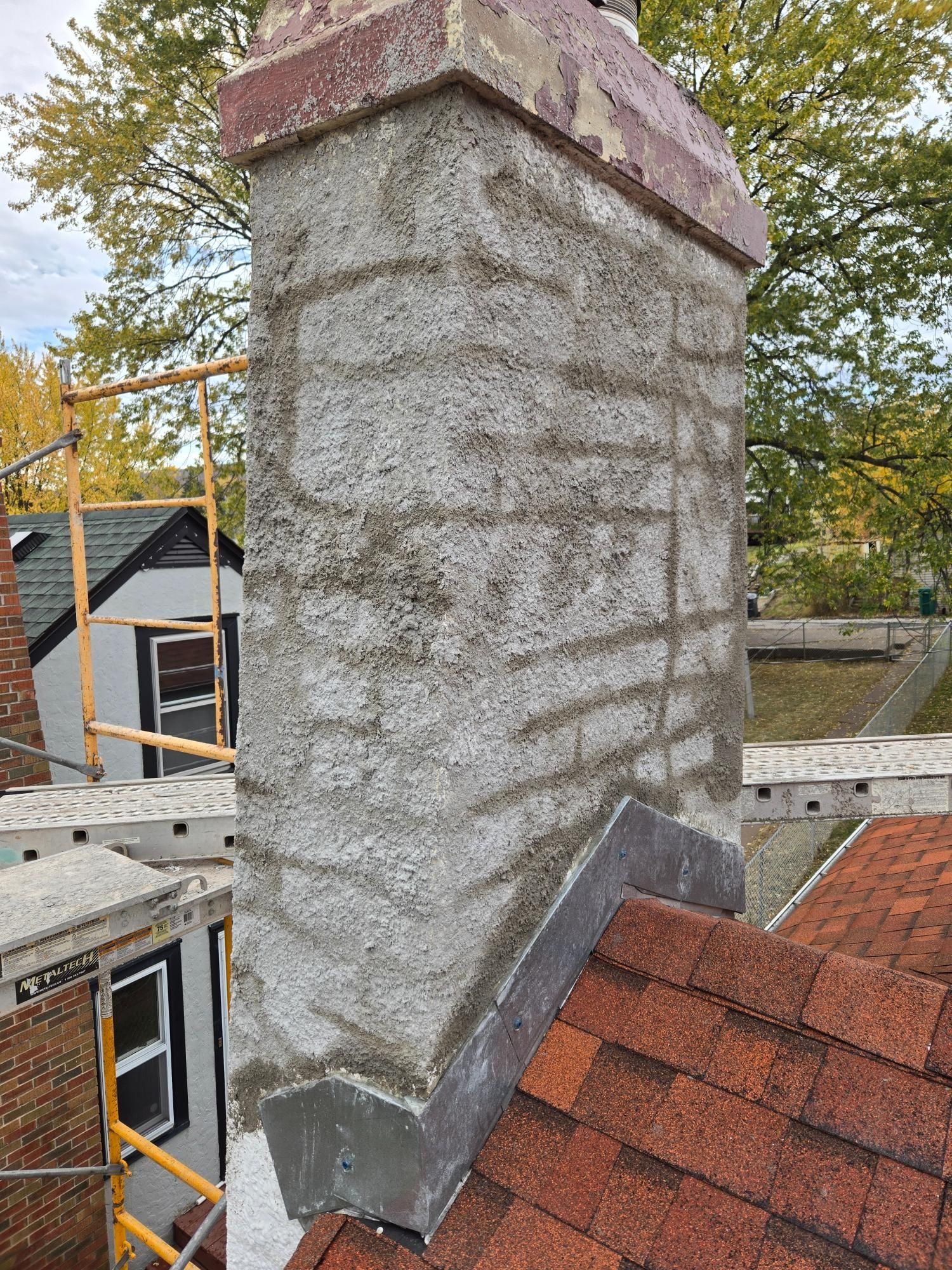 A chimney is being repaired on the roof of a house.