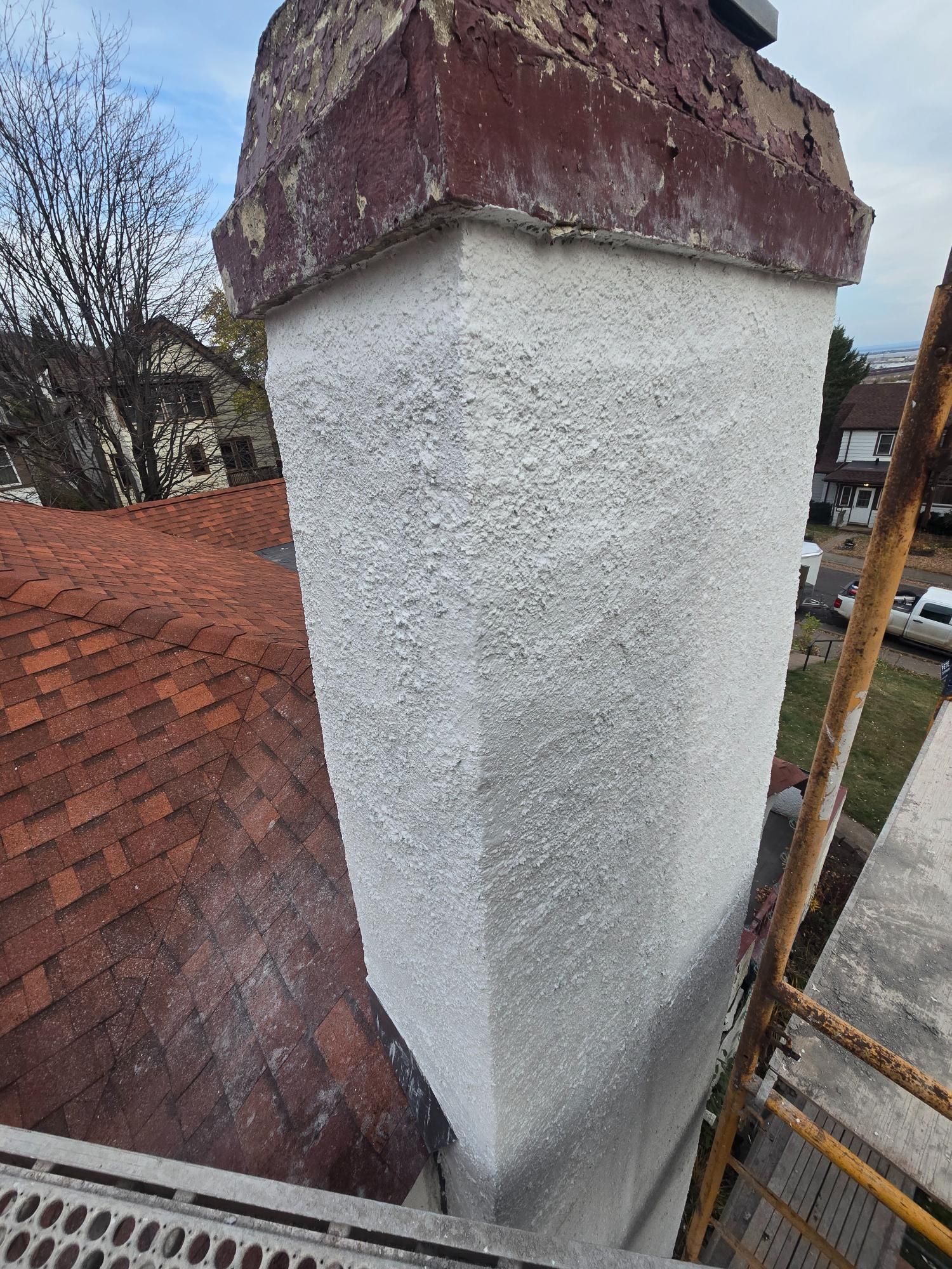 A white chimney is sitting on top of a brick roof.