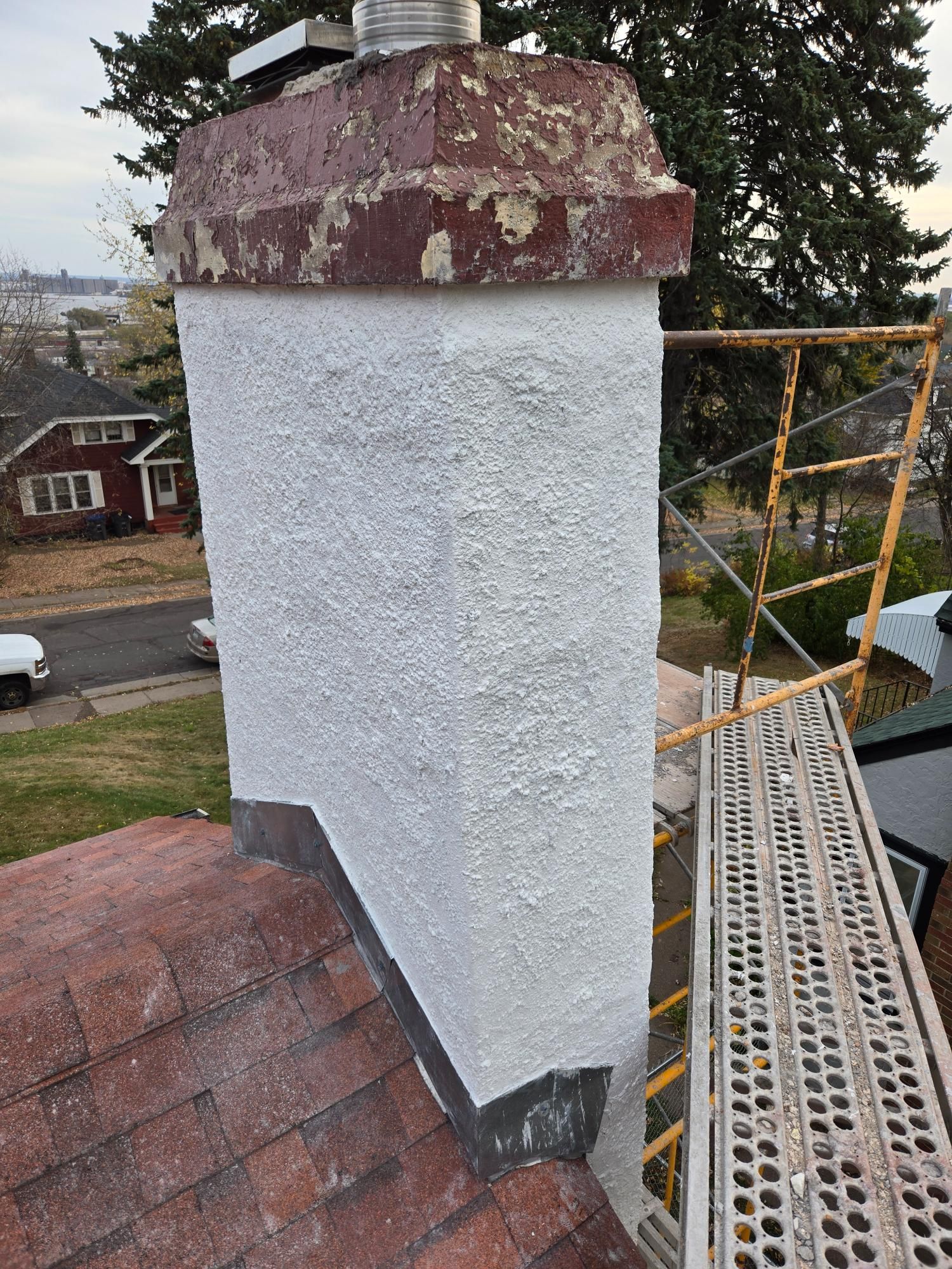 A chimney is sitting on top of a roof next to a scaffolding.