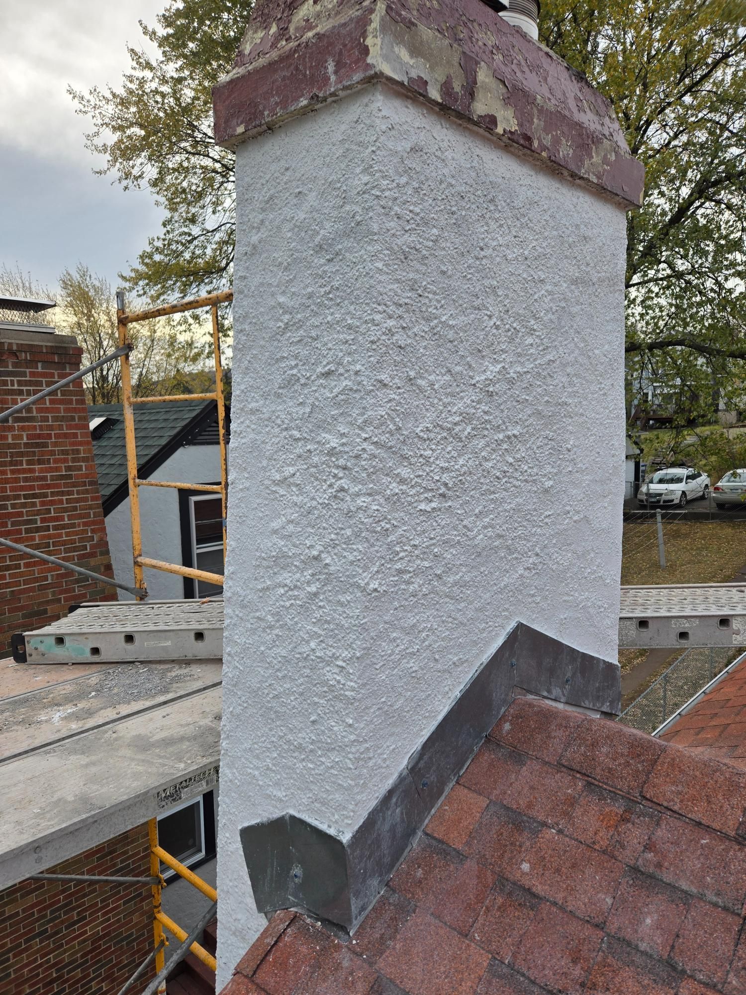 A chimney is sitting on top of a roof next to a scaffolding.