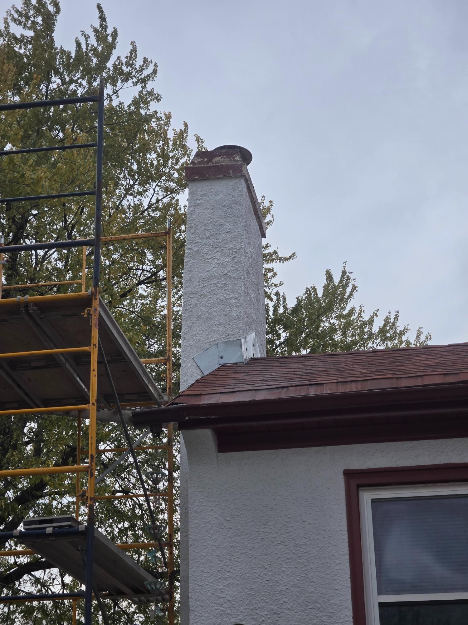 A chimney on the side of a house with a scaffolding behind it