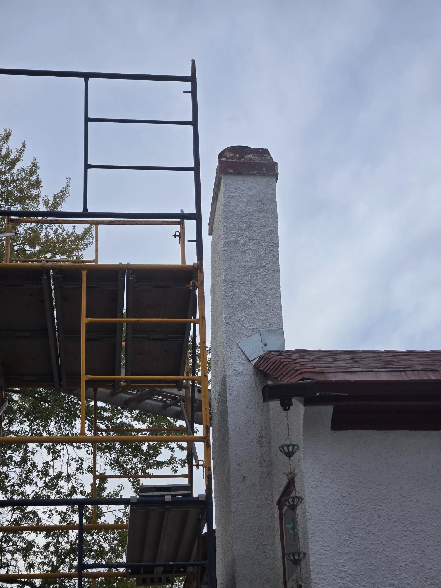 A scaffolding is sitting next to a chimney on the side of a building