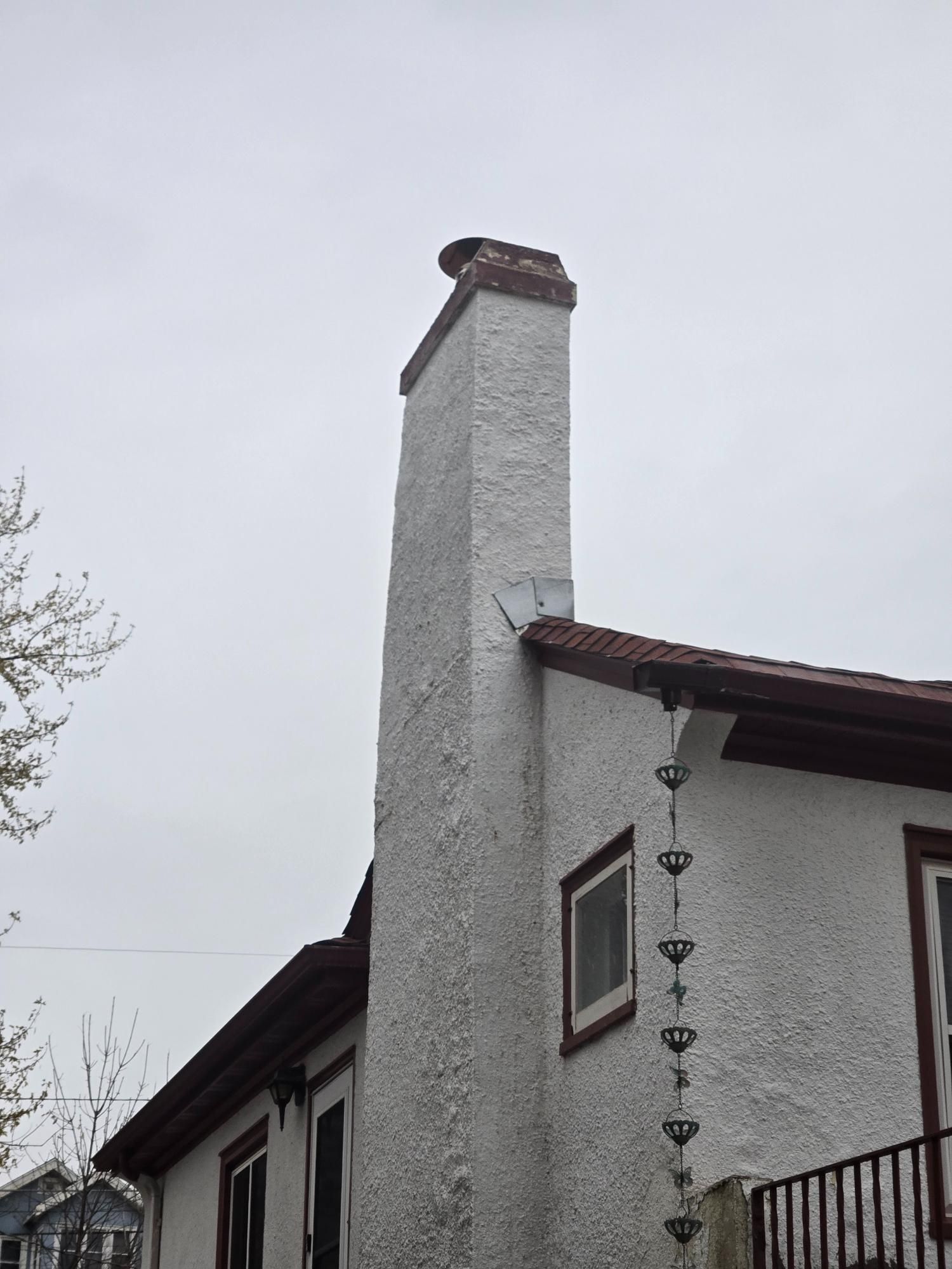 A white house with a chimney on the side of it