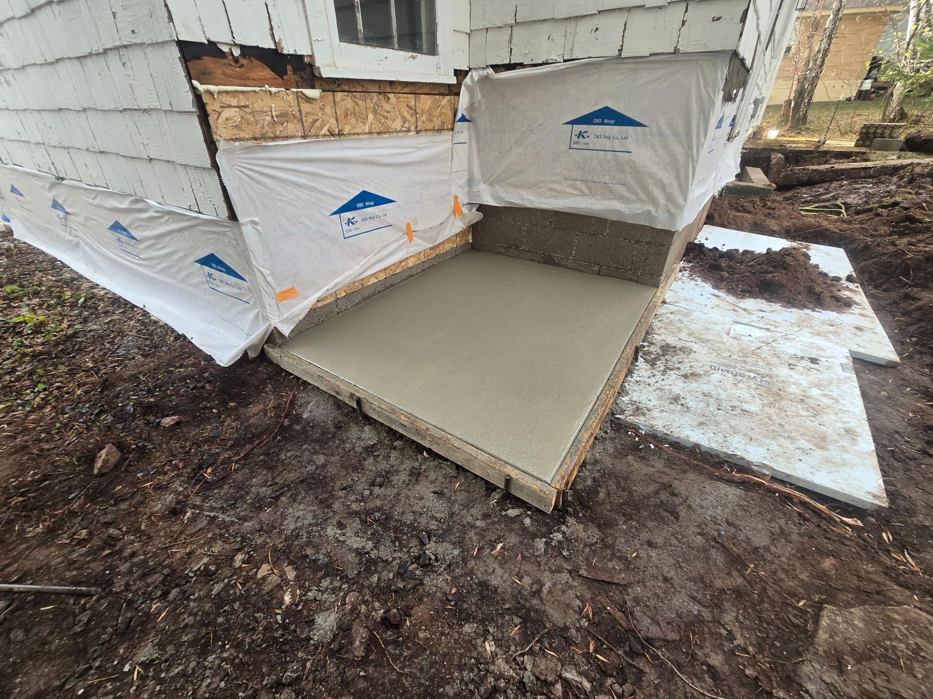 A concrete walkway is being built in front of a house.
