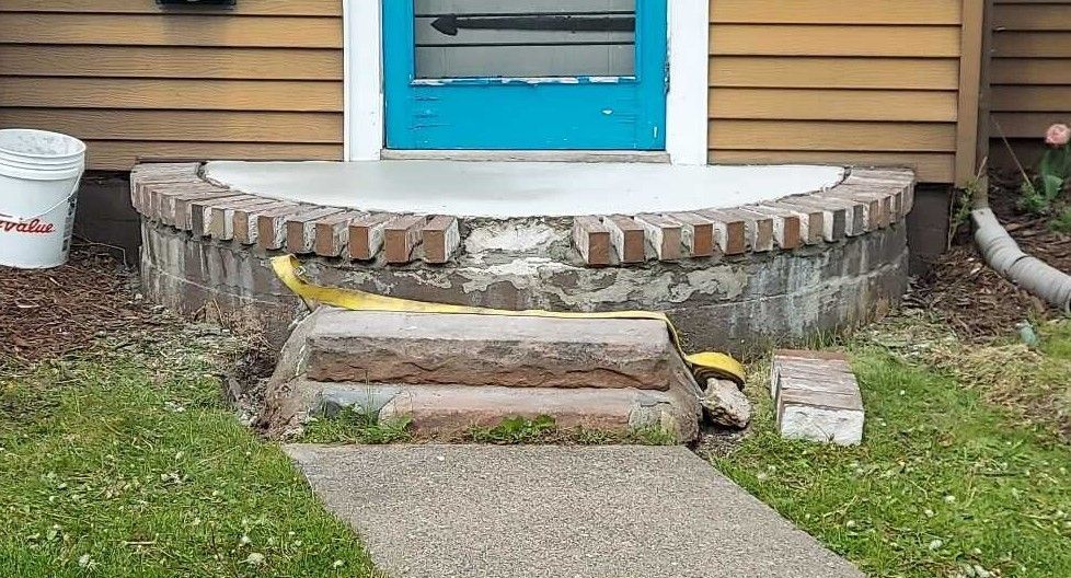 A concrete walkway leading to a blue door of a house.