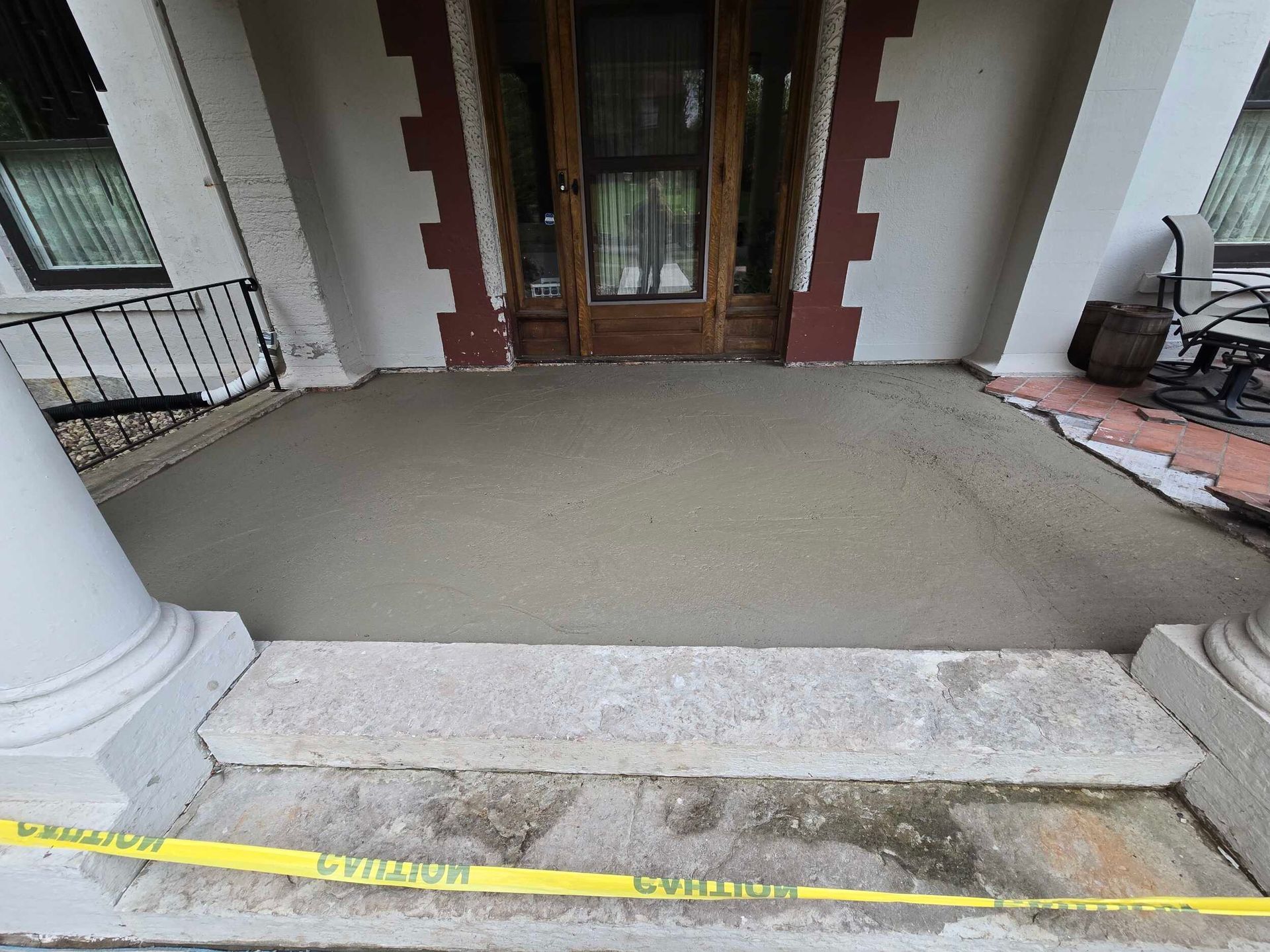 A concrete porch with a yellow caution tape around it.