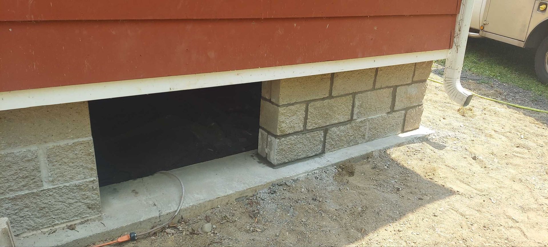 A brick wall with a hole in it next to a house.