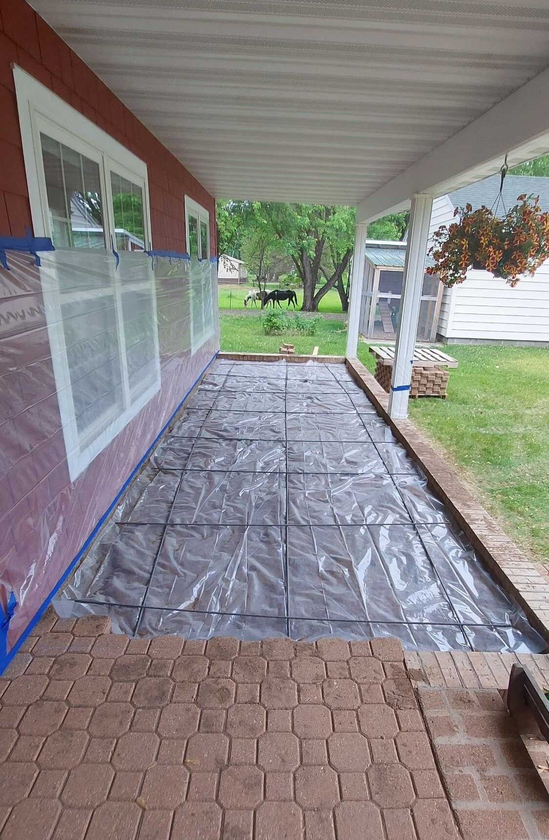 A porch with a brick walkway covered in plastic.